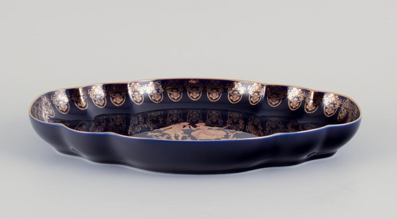 Limoges, France. Two porcelain serving platters adorned with 22-karat gold leaf and a beautiful royal blue glaze featuring Scène galante. 
Approximately 1970.
Provenance: From a large French private collection of Limoges porcelain.
Marked.
In