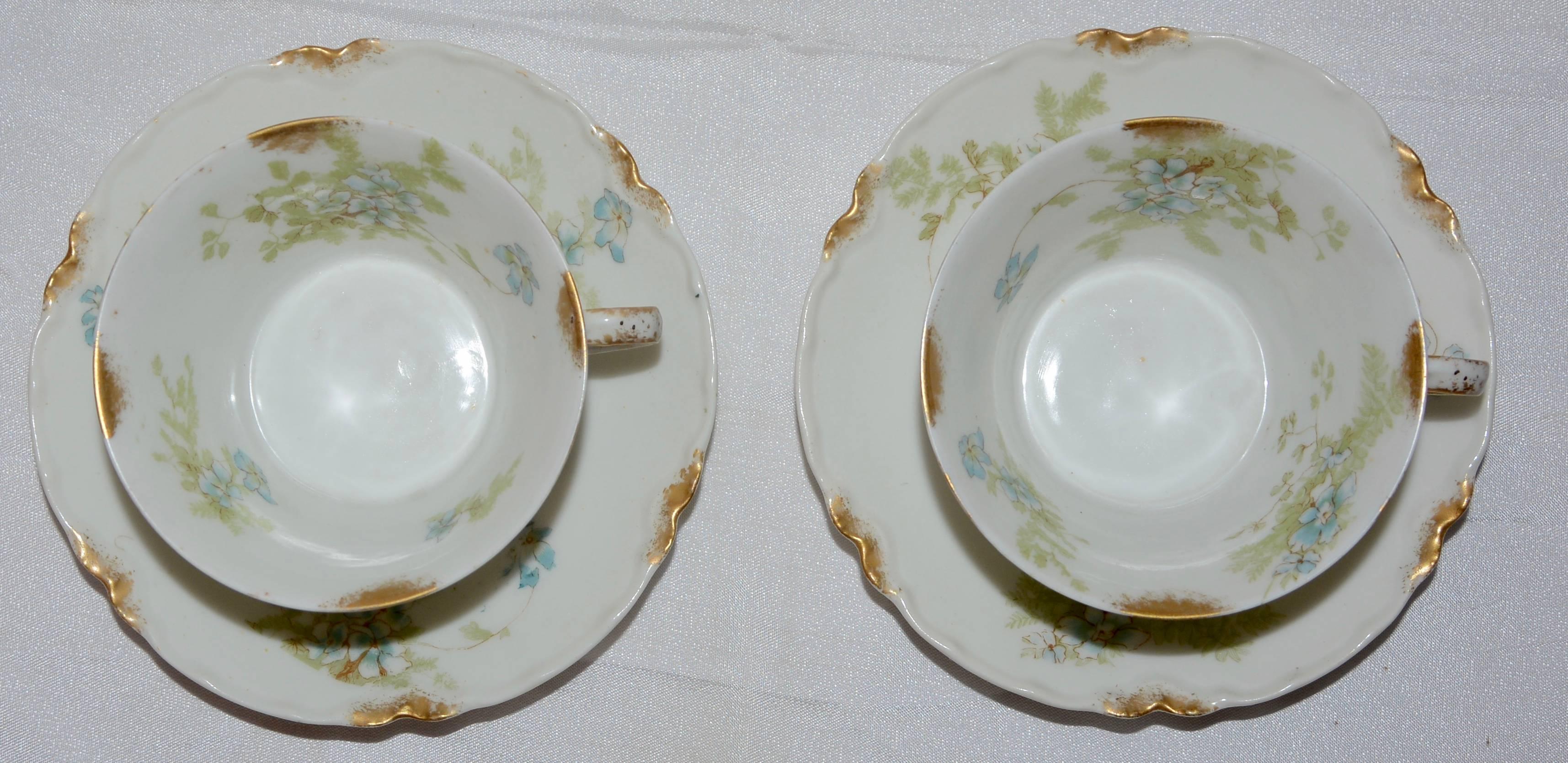 Delicate blue flowers with greenery surround this dainty set of porcelain and features accents of gold on the rims. This is a pair of demitasse cups and saucers with the porcelain by Haviland & Co. of France, Limoges and the decoration is by The Van