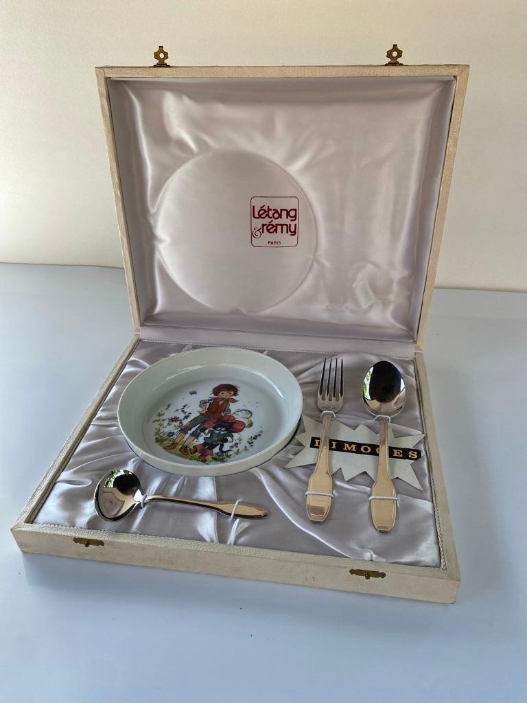 Vaisselle pour enfants dans sa boîte d'origine des marques françaises Limoges et Letang Remy. Une assiette/bol en porcelaine et une cuillère, une fourchette et une cuillère à bouillie en métal. Tous les articles sont en parfait état (non utilisés).