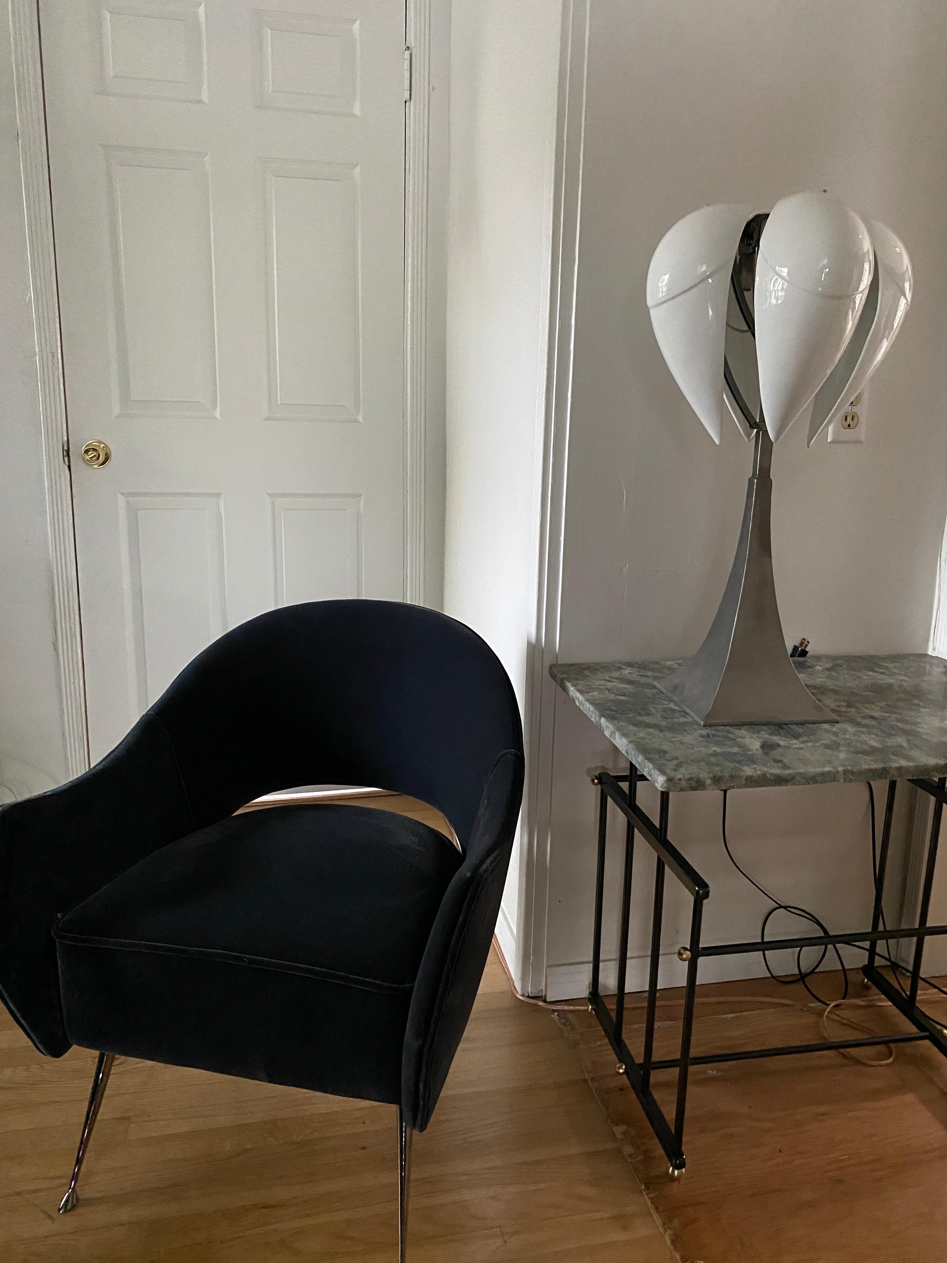La lampe Oyo de Pierrick Brocart est une lampe de table unique avec une base en acier poli et 4 diffuseurs en porcelaine de Limoges en forme de coquille. Le mécanisme articulé qui permet aux bras de se balancer vers le haut permet différentes