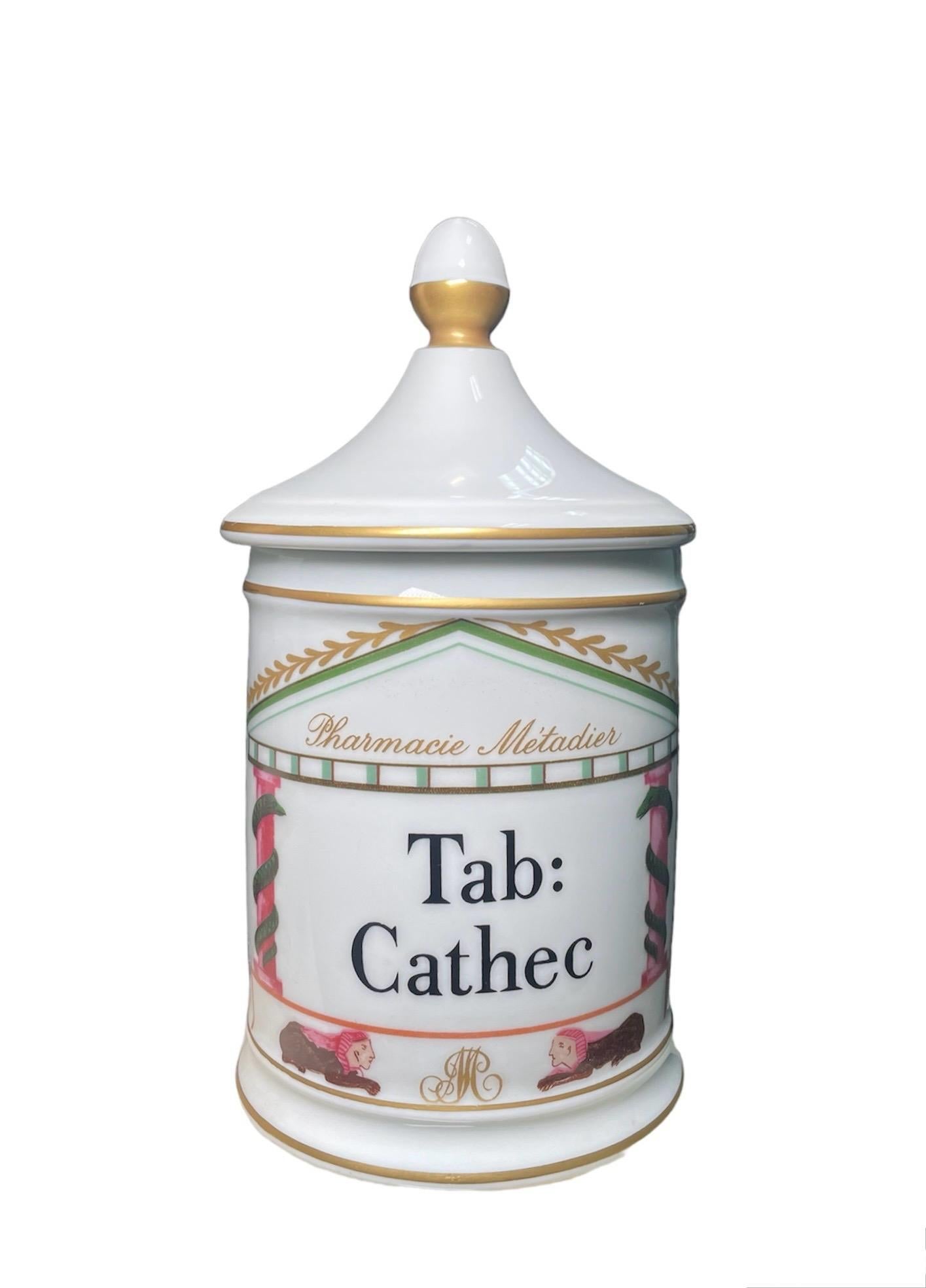 Questo è un vaso da farmacia in porcellana di Limoges. Raffigura un vaso di forma cilindrica con sfondo bianco e dipinto a mano con la facciata di un tempio greco al centro. Il nome latino di Tab:Cathec ( tavoletta ) tra due colonne ornate da