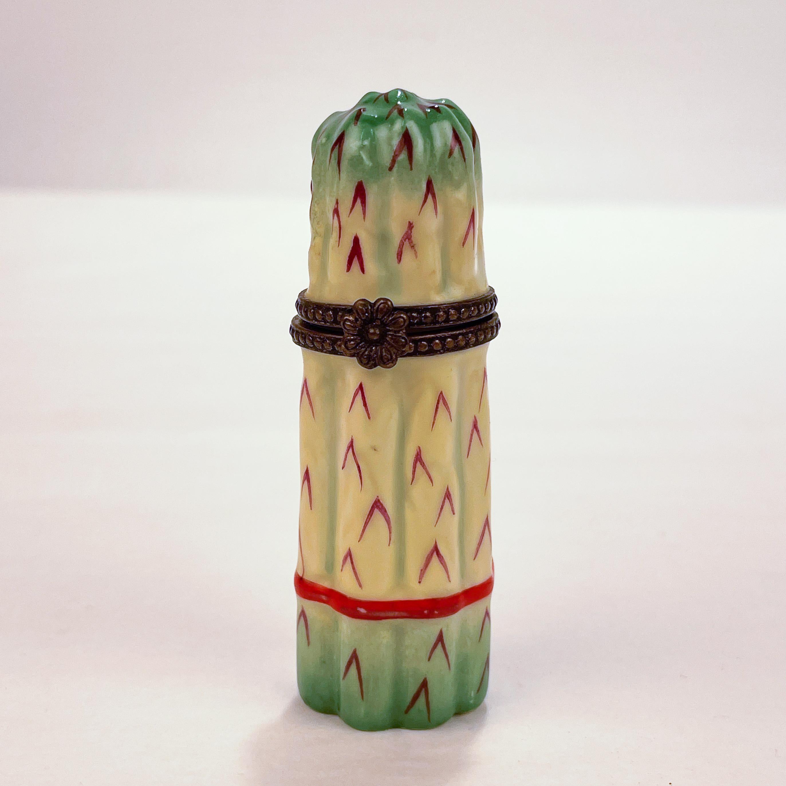 A fine, hinged Limoges porcelain traditional snuff box in the form of a bundle of asparagus. 

Retailed by Asprey.

Simply a lovely box!

Provenance: By repute, from the estate of Susan & John Gutfreund (The 'King of Wall Street').

Date:
Late 20th