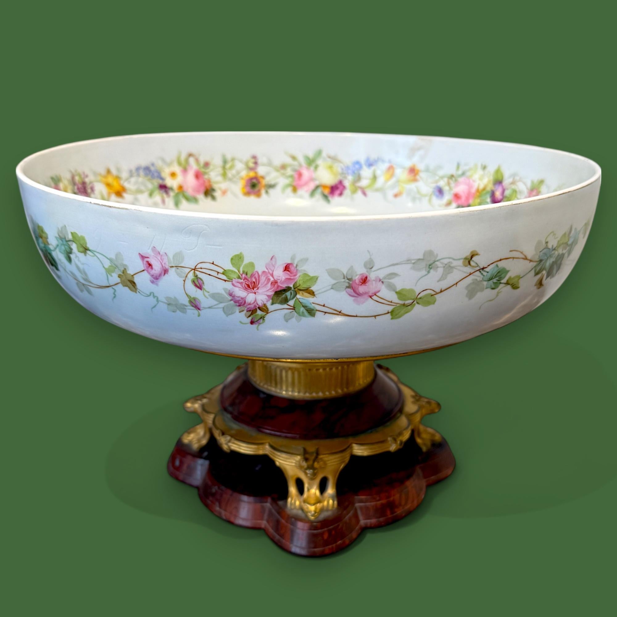 Cuenco de porcelana de Limoges con vibrantes motivos florales tanto en el interior como alrededor del borde. El cuenco está elegantemente montado sobre una base de mármol rojo intenso de Griotte, adornada con monturas de bronce dorado finamente