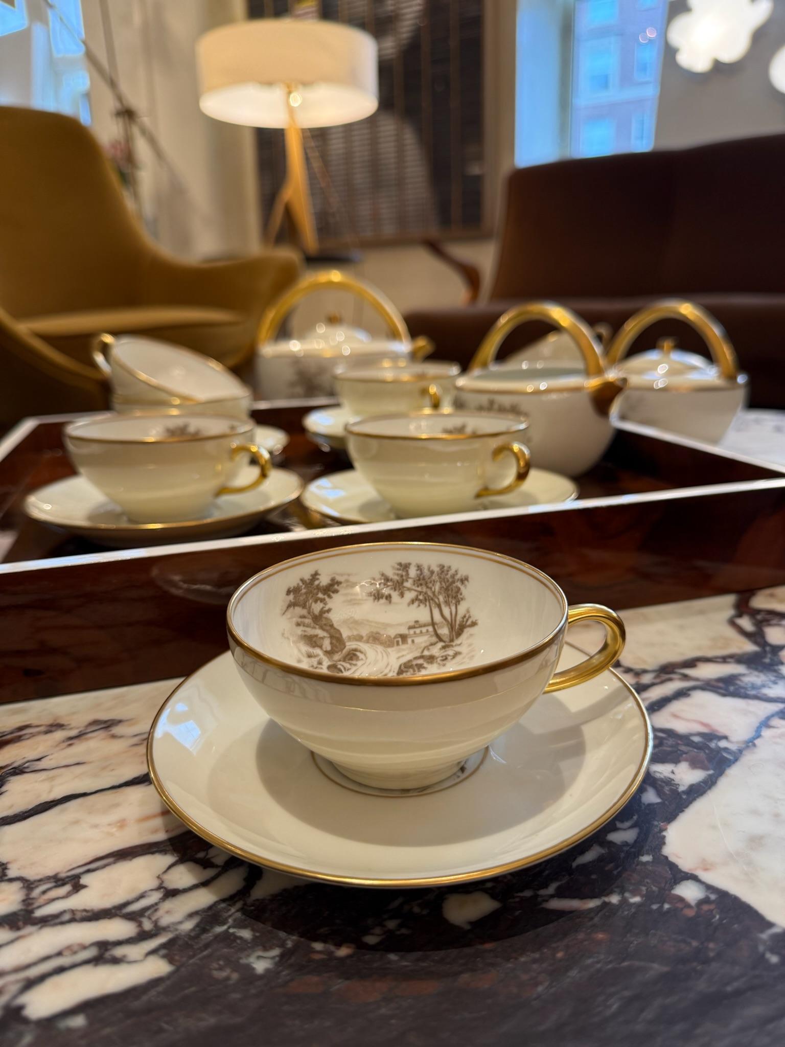 This refined Limoges porcelain tea set features a full service for eight, including eight cups with matching saucers, a teapot, a lidded sugar bowl, and a creamer. Each piece is crafted in luminous white porcelain, highlighted by hand-painted sepia