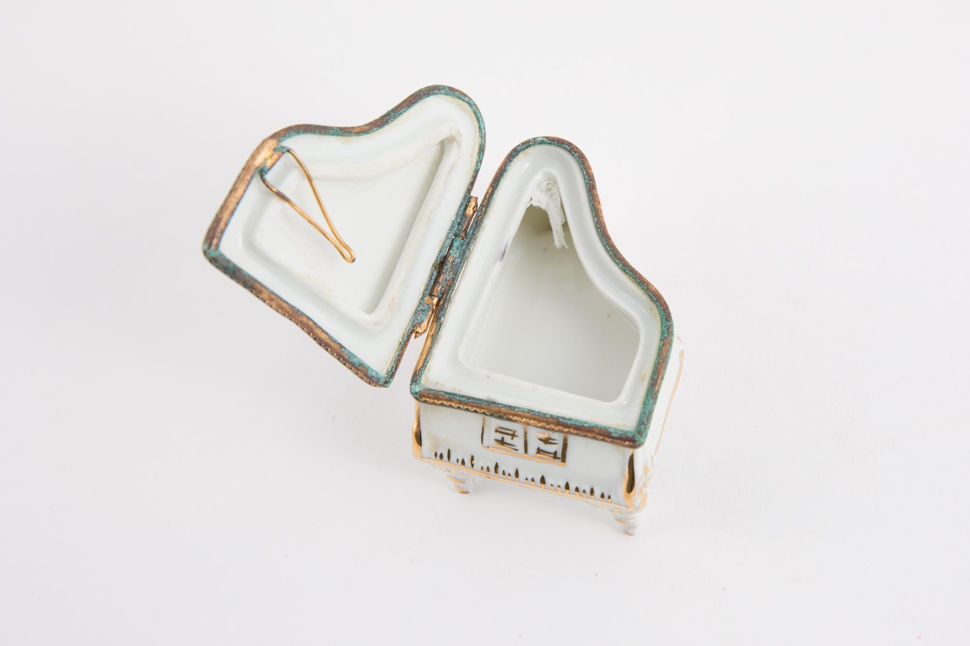 Limoges Singer porcelain piano shaped pill box featuring a gold metal frame with a gallant stage decor, a metallic gold tone hook to keep it open, a under stamp.
In good vintage condition. Made in France. 
Height Closed 1.5in. (4cm)
Maxi Width