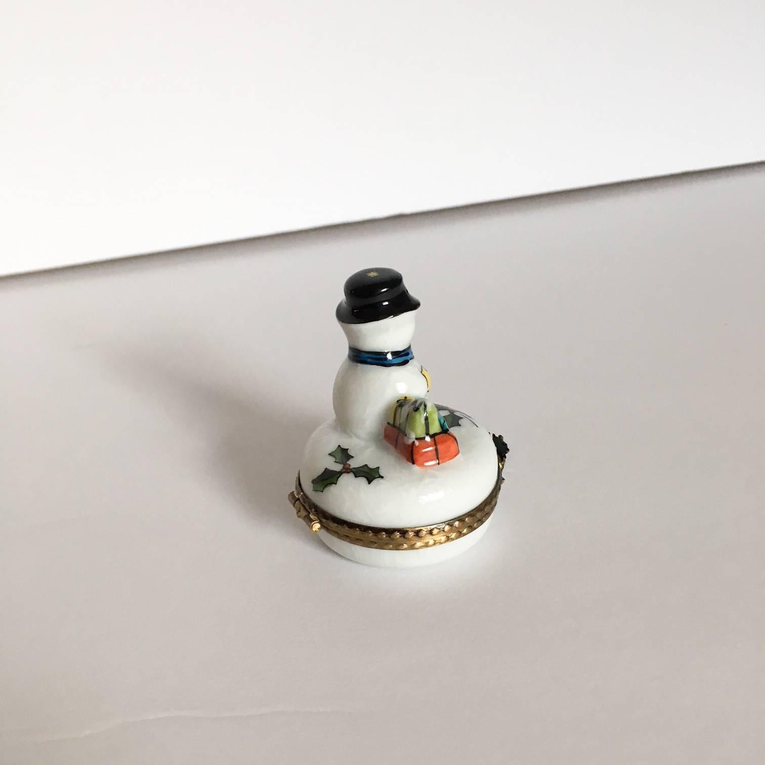 Delightful French Limoges box with brass hardware, hand-painted in France by Peint Main. Decorated with a snowman figure on the top, the clasp has a reindeer decoration with a hand-painted interior holly branch sprig on the inside bottom of the
