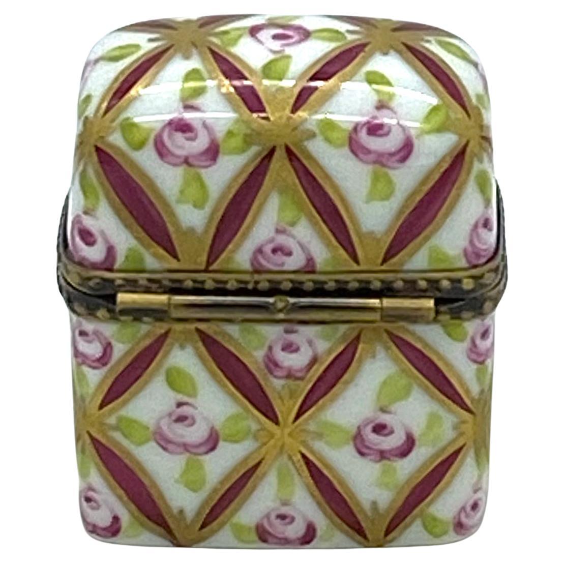 This is a Limoges trinket box with perfume bottles. Two small cranberry color bottles are set inside of this hand painted roses porcelain box. The brass hinge frame of the box has a flower motif clasp. The box is artist signed with 