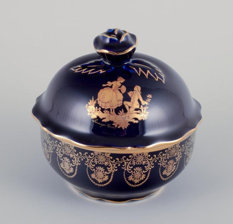 Limoges, Francia. Dos cajas / tarros de porcelana con tapa, decorados con pan de oro de 22 quilates y hermoso vidriado azul real. Escena galante. 
Aproximadamente 1970.
Procedencia: Procedente de una gran colección privada francesa de porcelana de