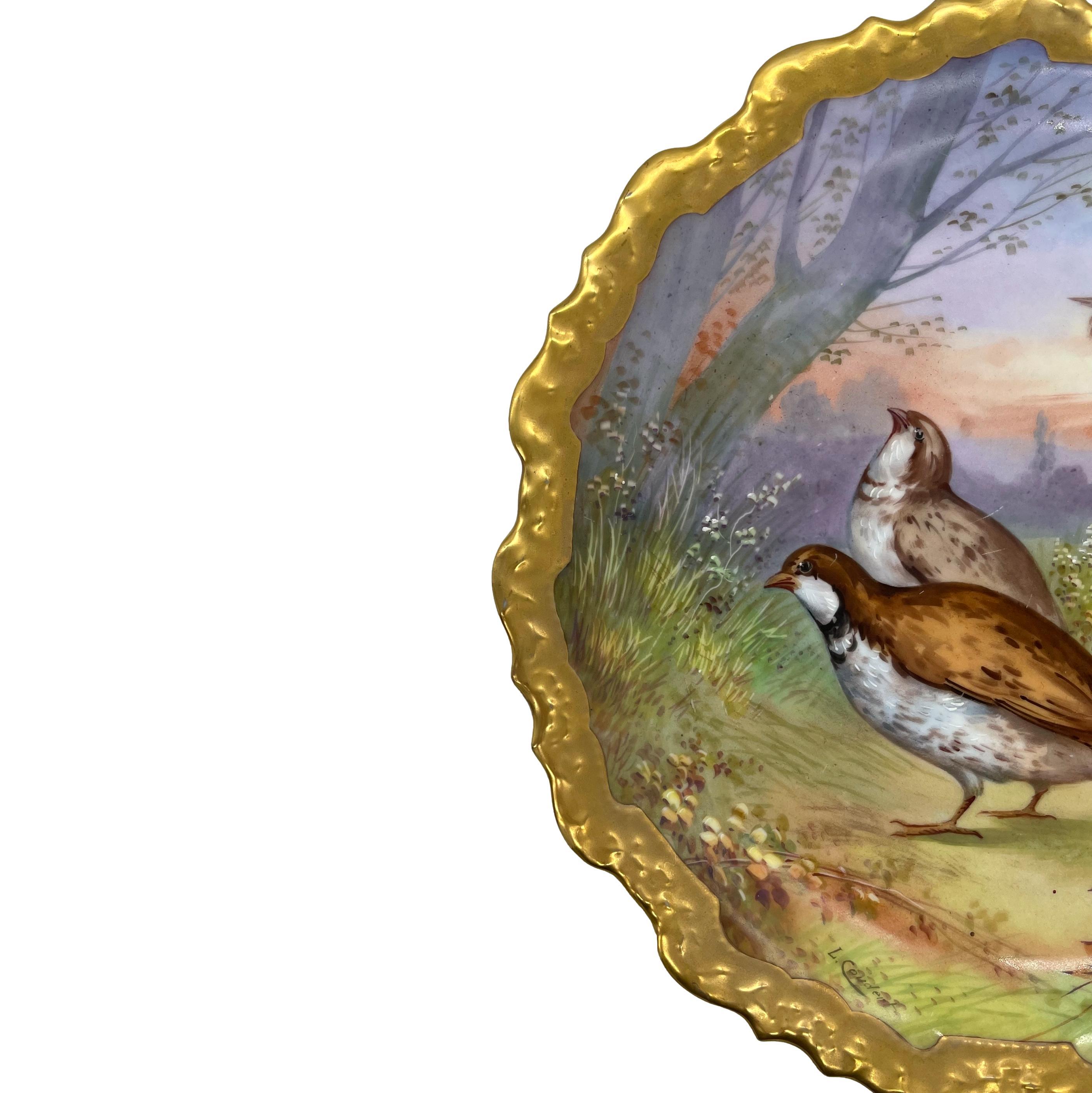 Limoges porcelain wall charger, hand-painted with a pair of Quails in a sunset landscape, with artist signature, 'L. Coudent,' with heavy gilding to the shaped border, the reverse with painted mark, 'Limoges France C et J,' and the foot rim with