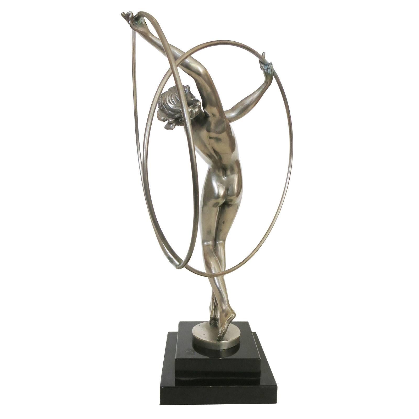 Limousin Art Deco style silver nude flapper dancer with hoop statue in the manner of Max Le Verrier.
This gorgeous looking statue features a cast bronze nude flapper statue with an antique silver finish. This sculpted figure stands on top of a black