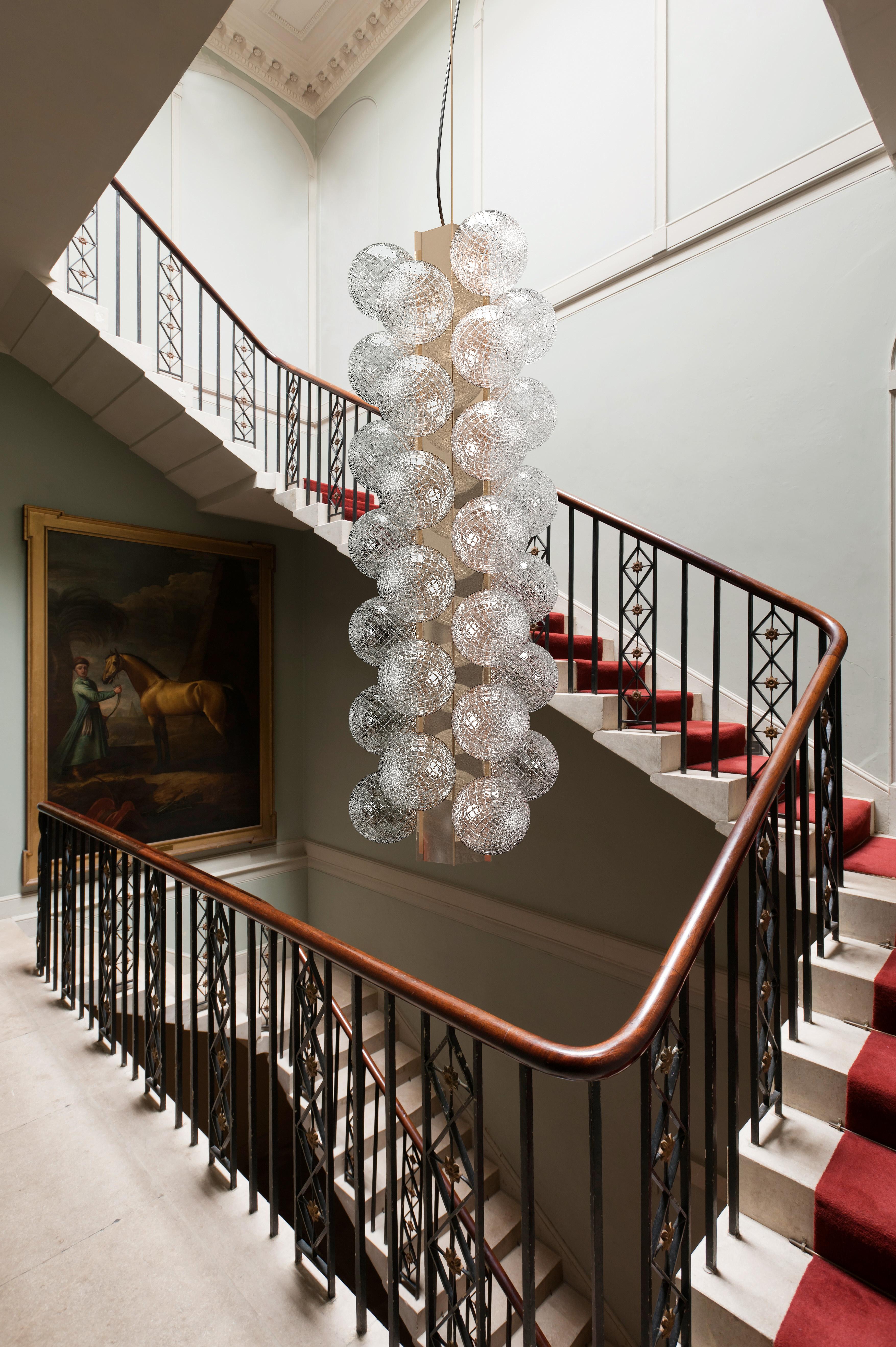 Inspired by Philip Johnsons interiors, the sophisticated vertical suspension Lincoln is elegant but discreetly playful. The blown glass spheres, applied alternately on either side of the central structure, are worked with the balotòn technique which