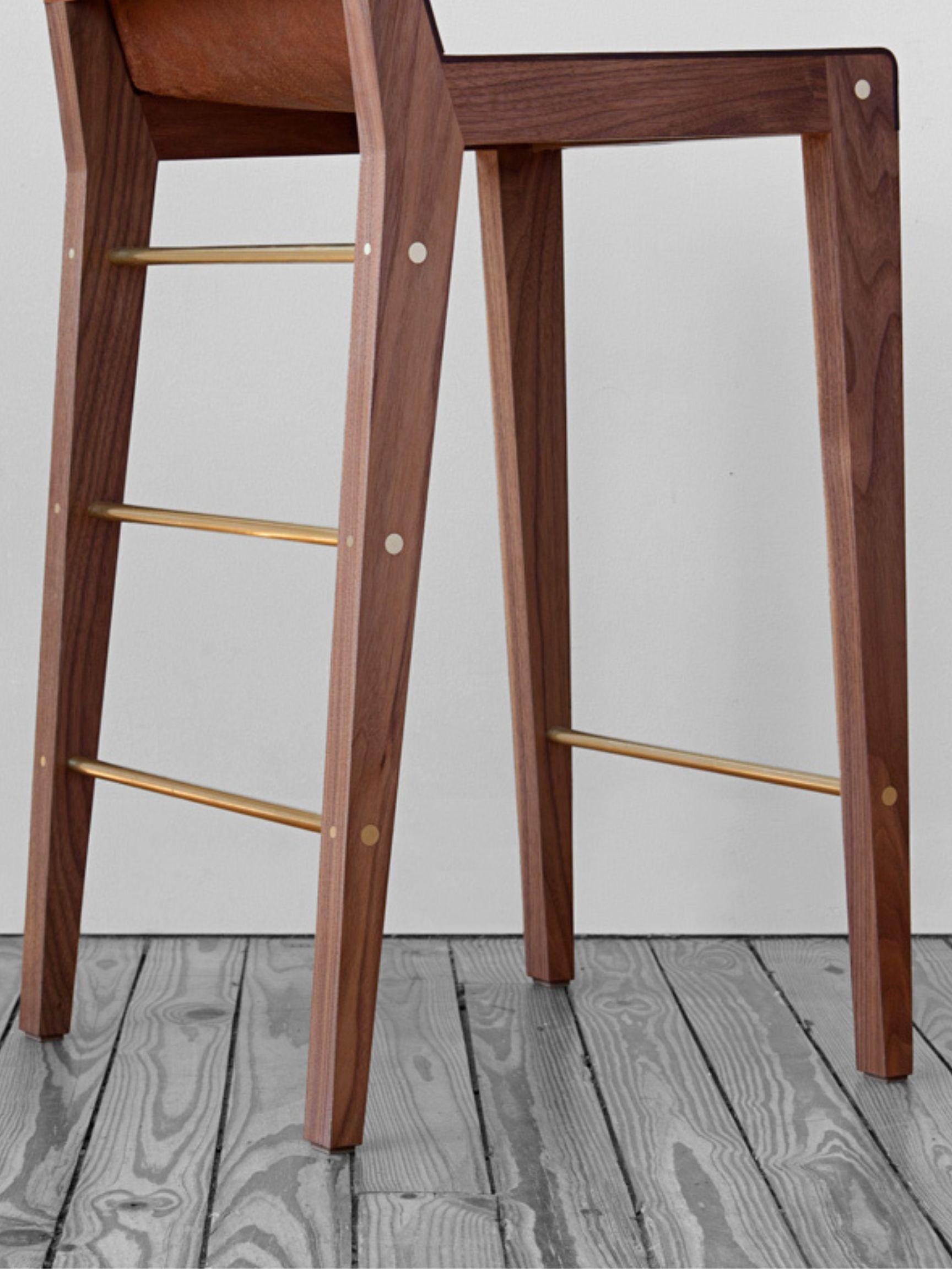 A simple chair to sit in grandeur. The leather seat curves around a black walnut frame while hints of brass shine from within. Handcrafted stool manufactured in Brooklyn, NY by Asher Israelow. A custom design, combining the back of the Lincoln chair