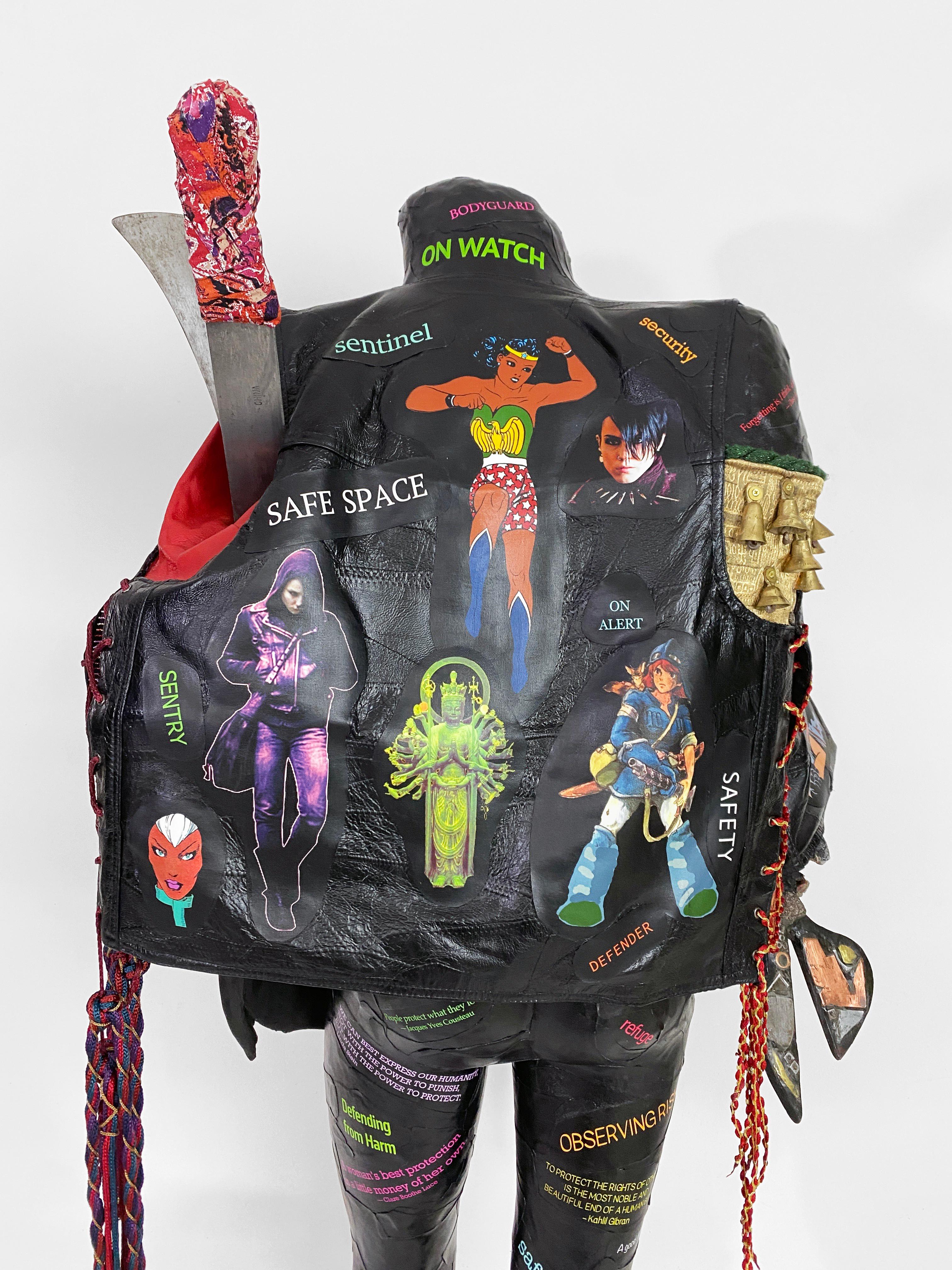 Linda Stein, Guerriero che porta la pace: Affrontare la protezione 1282  - Scultura contemporanea femminista figurativa a tecnica mista nera e colorata 

Scultura contemporanea autoportante con gilet che include immagini di fumetti di Wonder Woman e