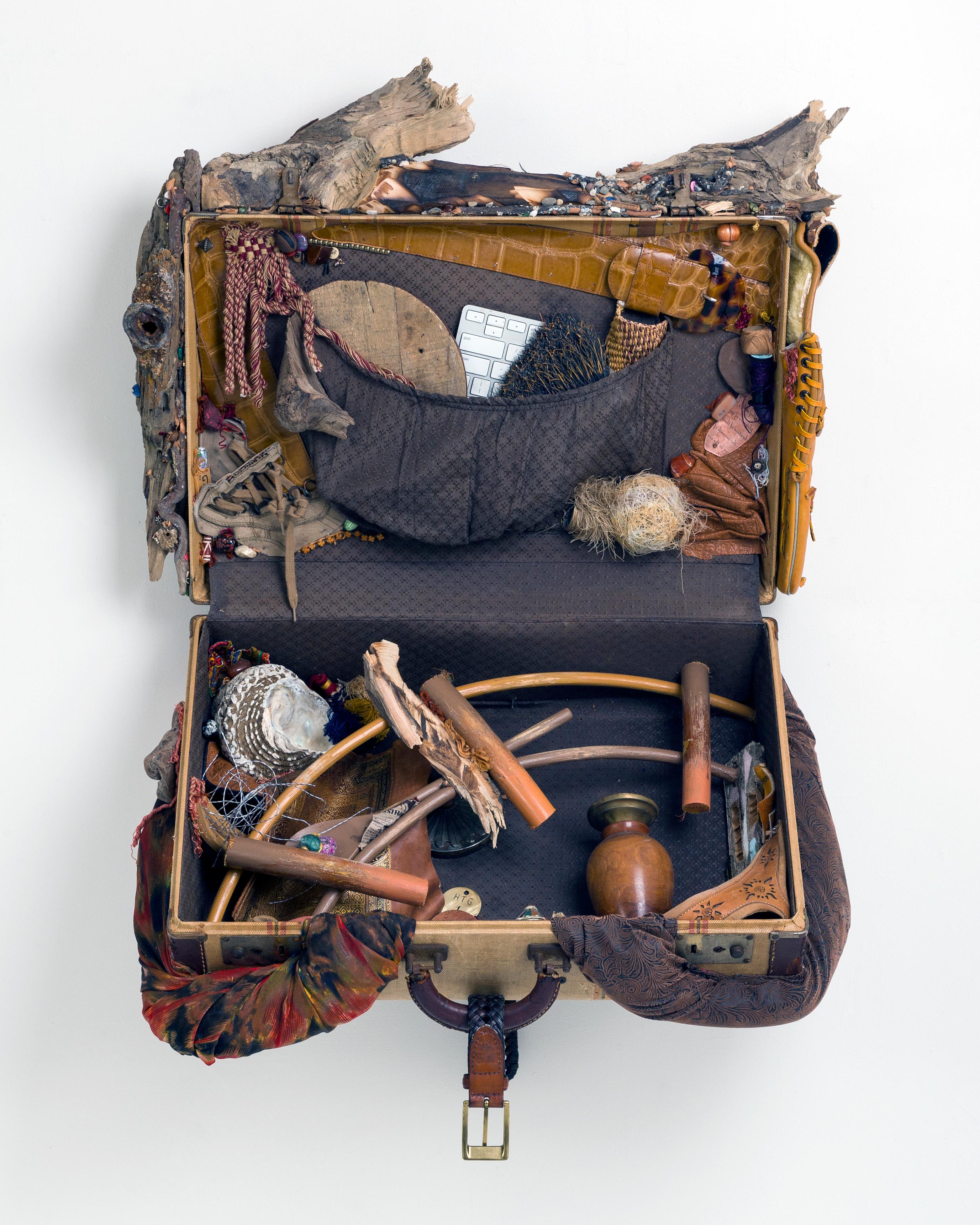 Esta obra de la serie Desplazamiento del Hogar de Linda Stein se inspira en la tradición de las wunderkammer/armarios de curiosidades para poner de relieve el desplazamiento global y la memoria traumática de los emigrantes y refugiados de todo el