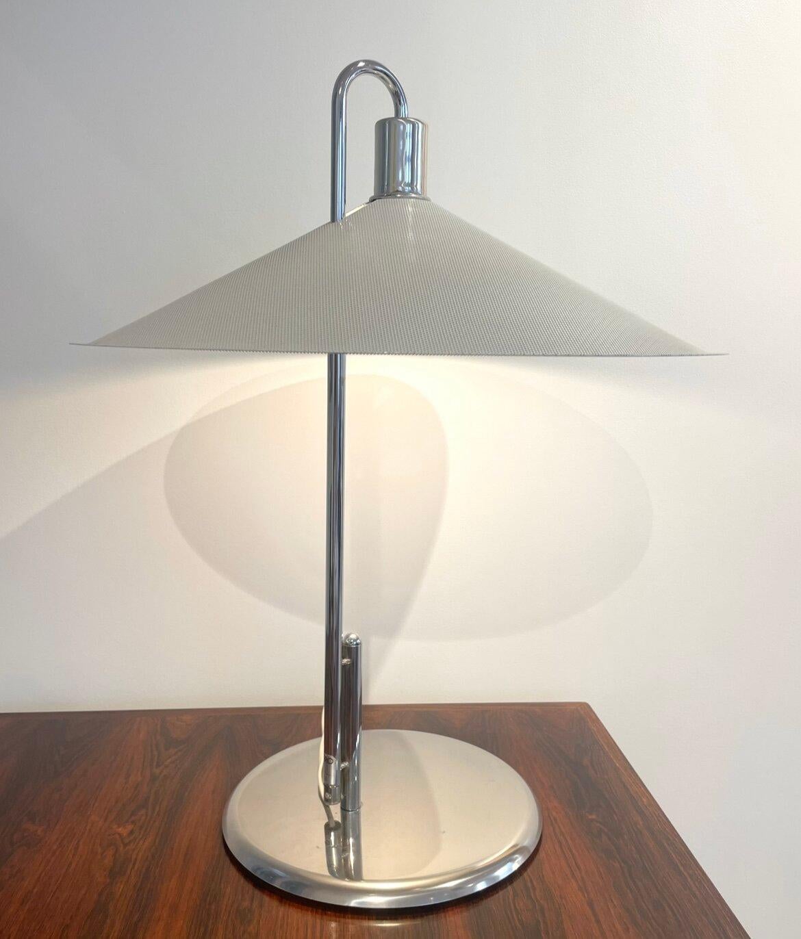 Diese von den schwedischen Designern Lindau und Lindekrantz in den 70er Jahren für den Verlag Zero entworfene Tischleuchte hat eine sehr grafische Linie, die durch den großen Lampenschirm aus lackiertem und perforiertem Metall noch verstärkt wird.