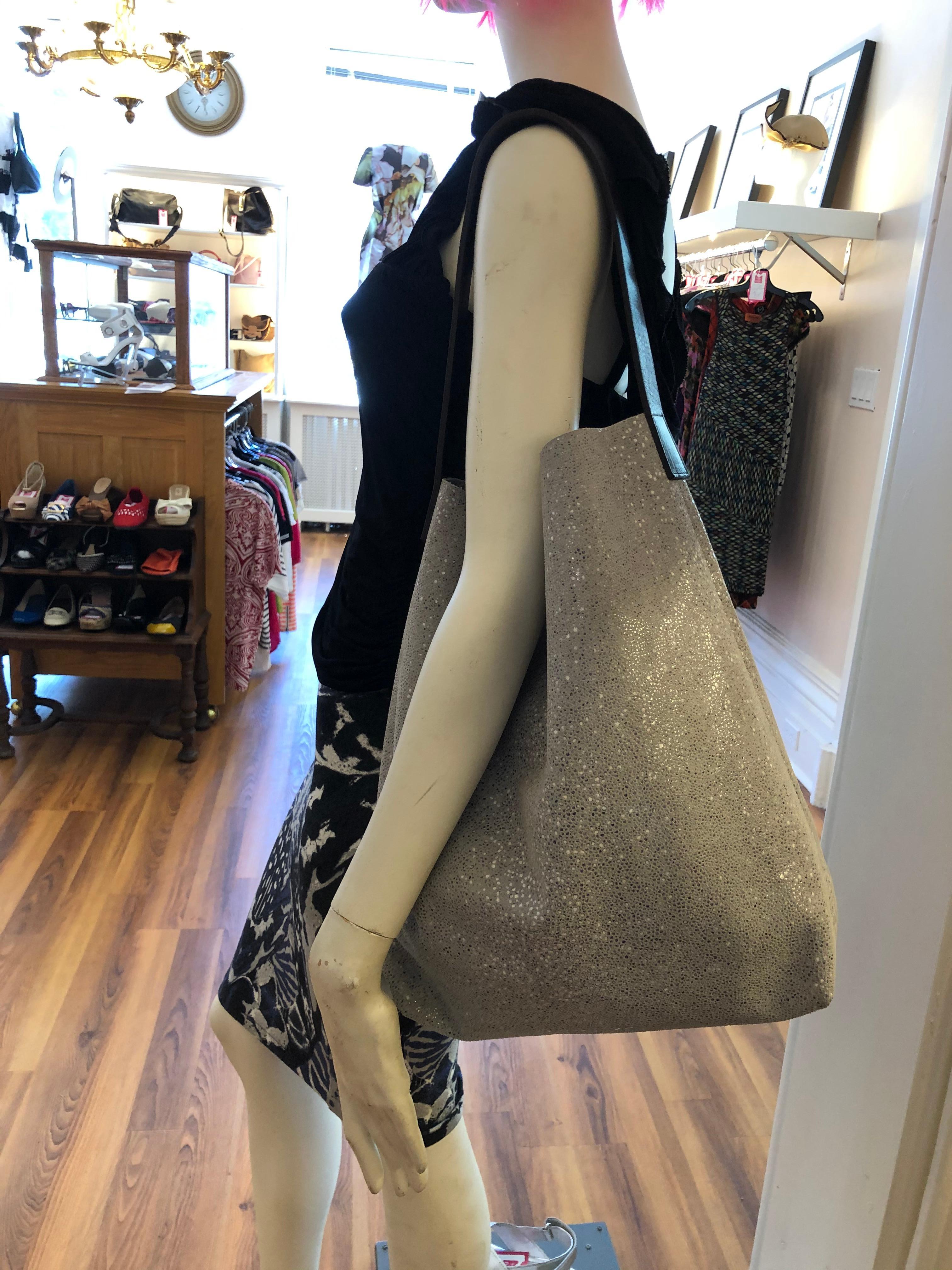 The Linde Gallery St Baths Hobo Bag is made in France of printed velvet leather with a leather shoulder strap (see 2nd picture). There is an inside zip pocket and a light resin finish which make this silver/grey colored bag sparkle.

The bag is