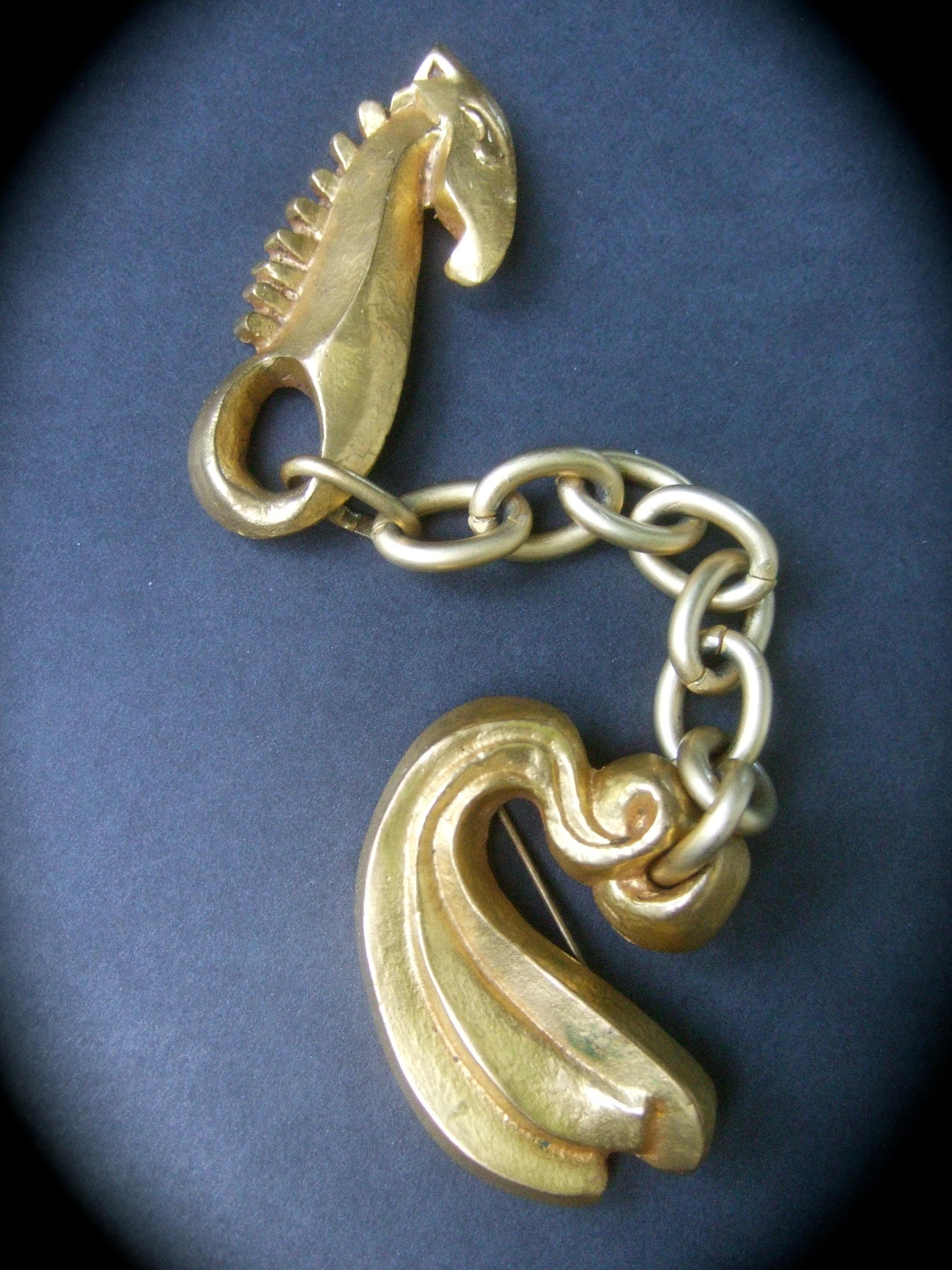 Line Vautrin 1940s Art Deco articulated gilt bronze seahorse brooch (Attributed)

The incredibly rare figural brooch is designed with a stylized gilt bronze seahorse figure. Suspended from a dangling chain is a sinuous grooved curved tail