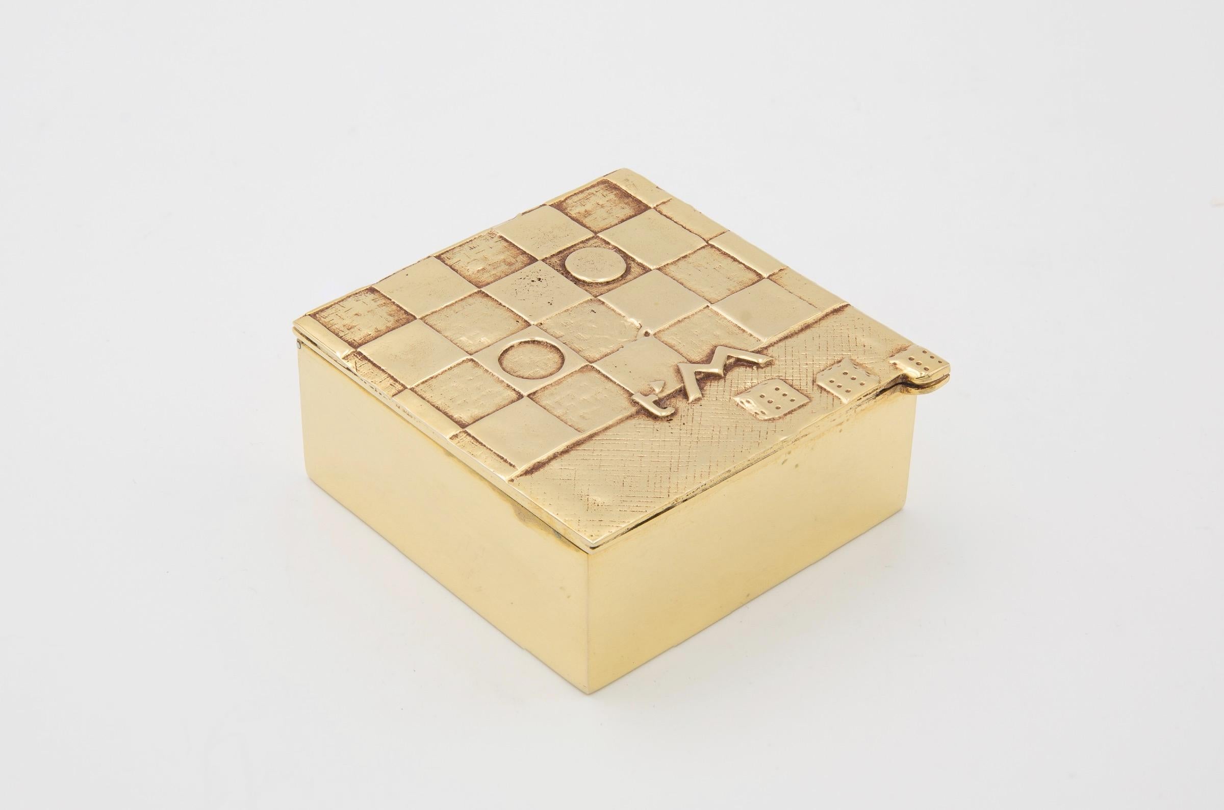 Je t'aime Beaucoup, a scarce gilded bronze box by Line Vautrin.
The box depicts a rebus message
Jeu for the game
t'm for t'aime
Beau coup because of the triple six on dices
So ... Jeu t'm beau coup means in poetic rebus langage 