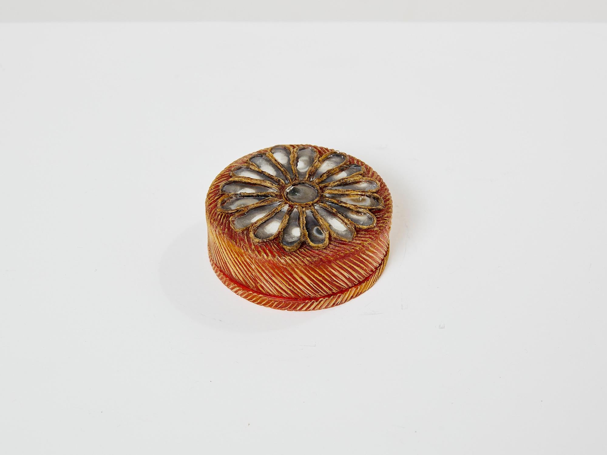 Pretty little roud box by Line Vautrin made in the 1960s. It is circular in shape, in orange tinted talosel, the lid inlaid with fragments of dark grey tinted mirror forming a marguerite or daisy flower, the bottom of the box centred with a fragment