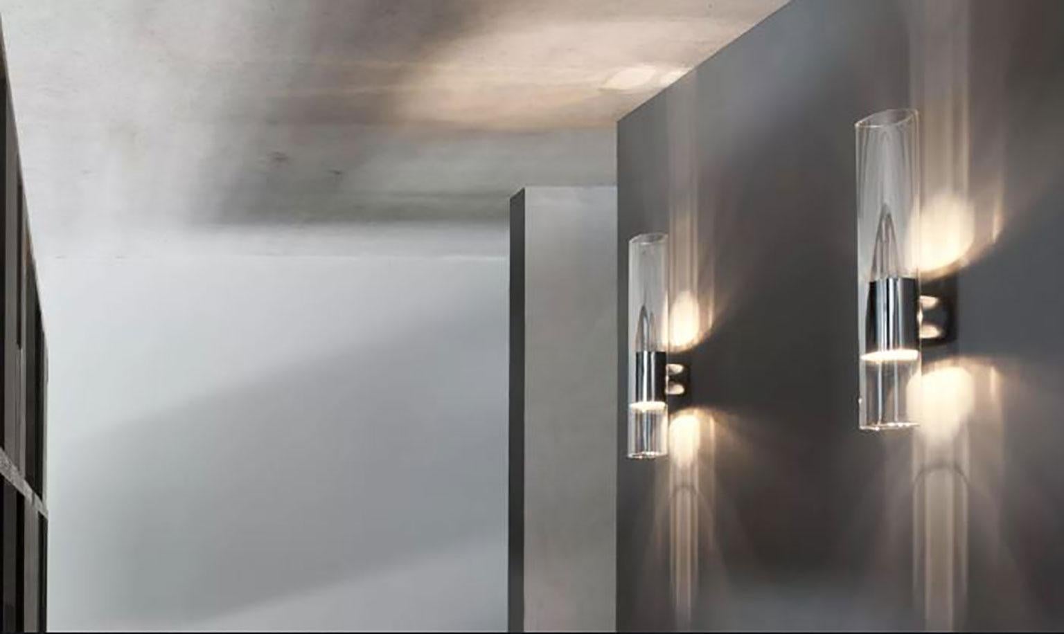 Applique Line conçue par Francesco Rota pour Oluce. Le design de cette lampe est parfaitement minimaliste. La lampe est fabriquée en verre Pyrex ovale spécial. La structure en aluminium au centre de la lampe se fixe au mur. En outre, la structure en