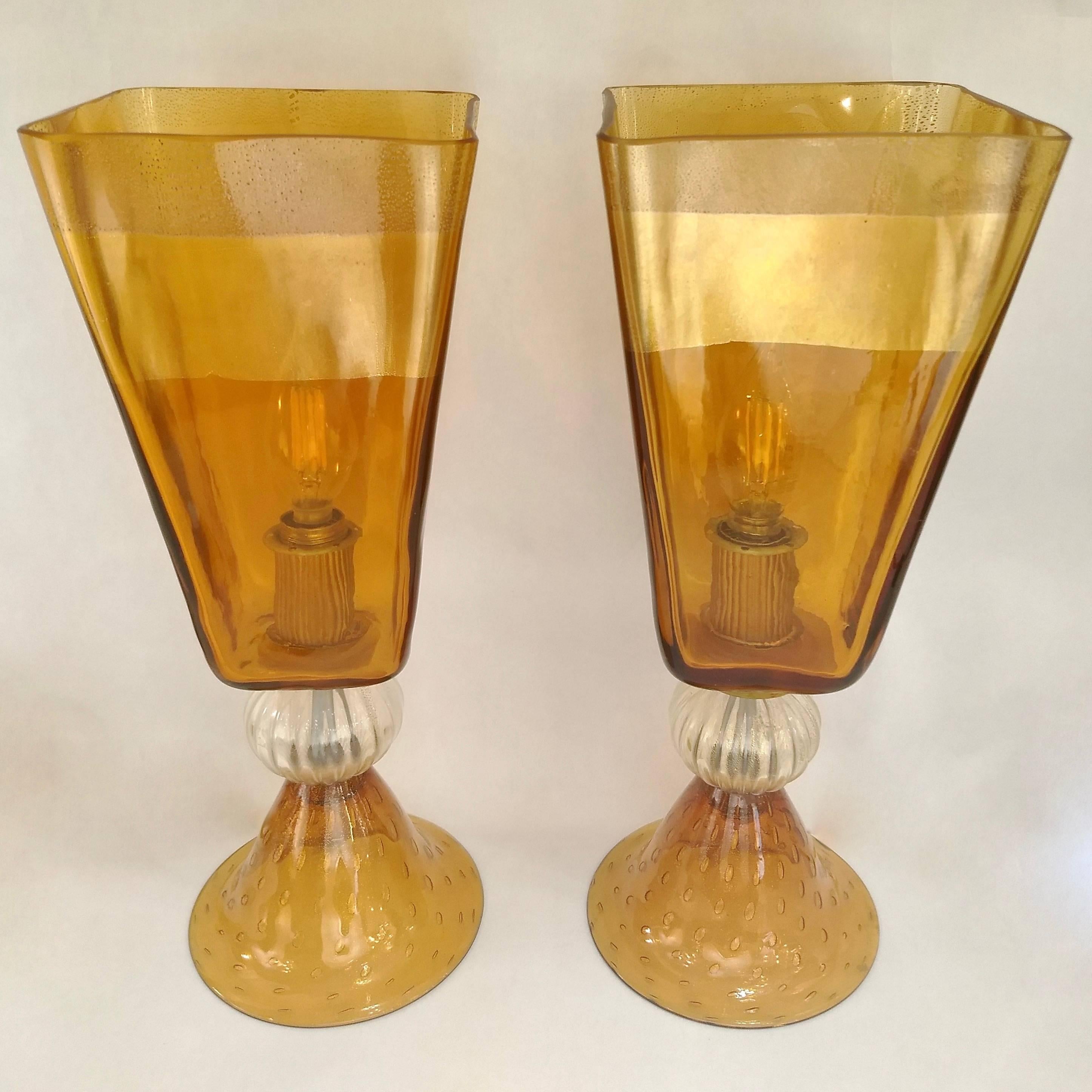A delightful vintage pair of Italian design table lamps, ideal for nightstands or desk use, high quality of execution in blown Murano glass worked with pure 24-karat gold in the amber glass body distributed with varied concentration to produce a