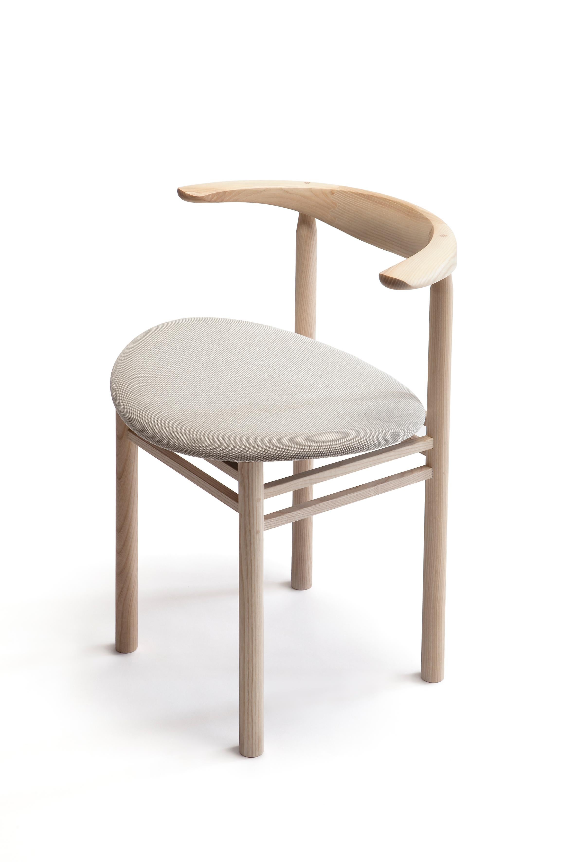 Linea RMT3 chair is designed by Rudi Merz in 2009. Its curved backrest enhances seating comfort. The seat is always upholstered, and the frame is from northern European ash. Wooden joints and nails are visually beautiful and structurally