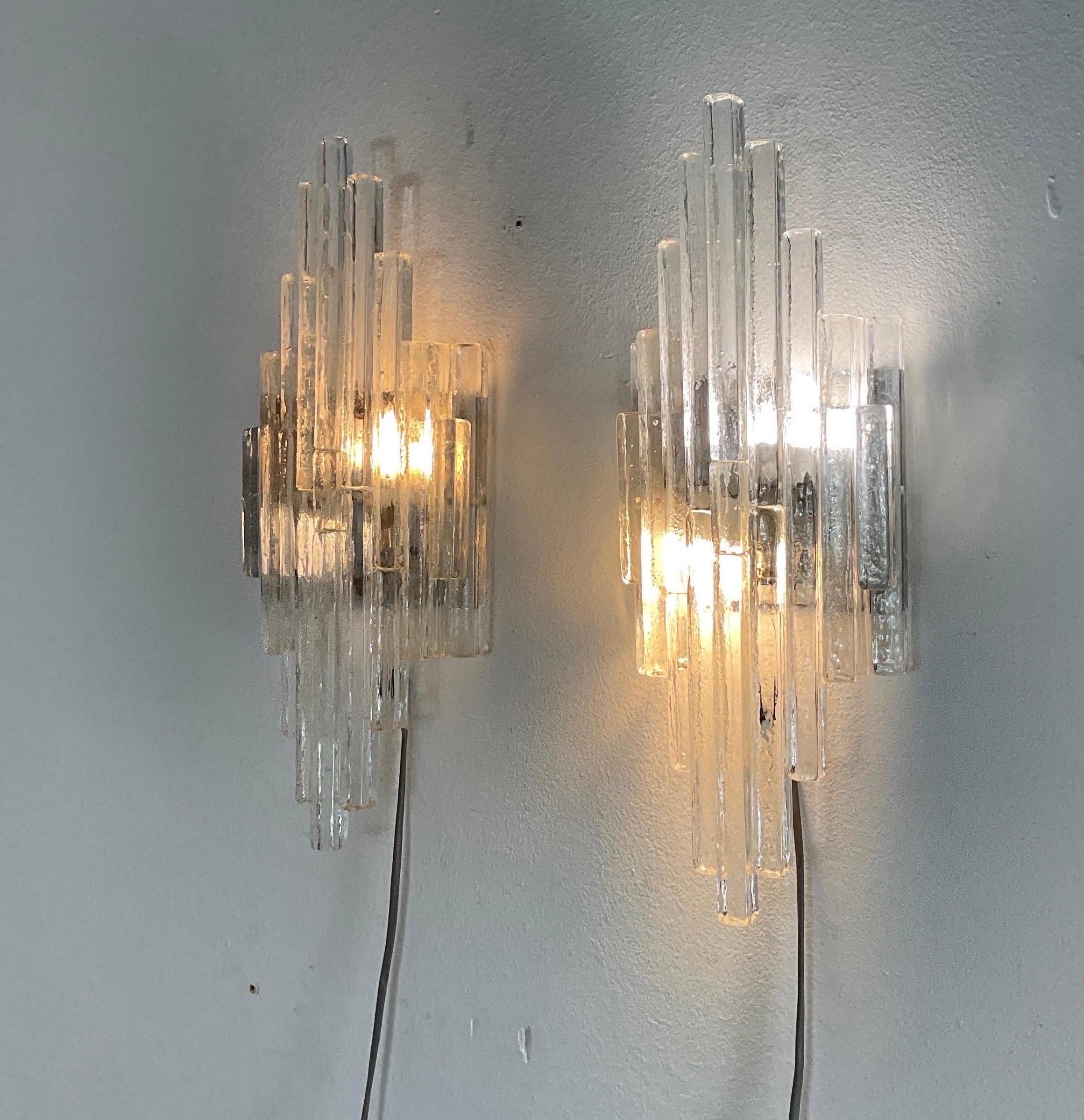 Linea' series wall lamps, Poliarte Production, Verona, '70s. Transparent raw crystal wall lamp, satin stainless steel backing, elongated in shape, two lights,H cm 49x18x10 (wear) Bibliography: Poliarte Catalogue, 1974.
