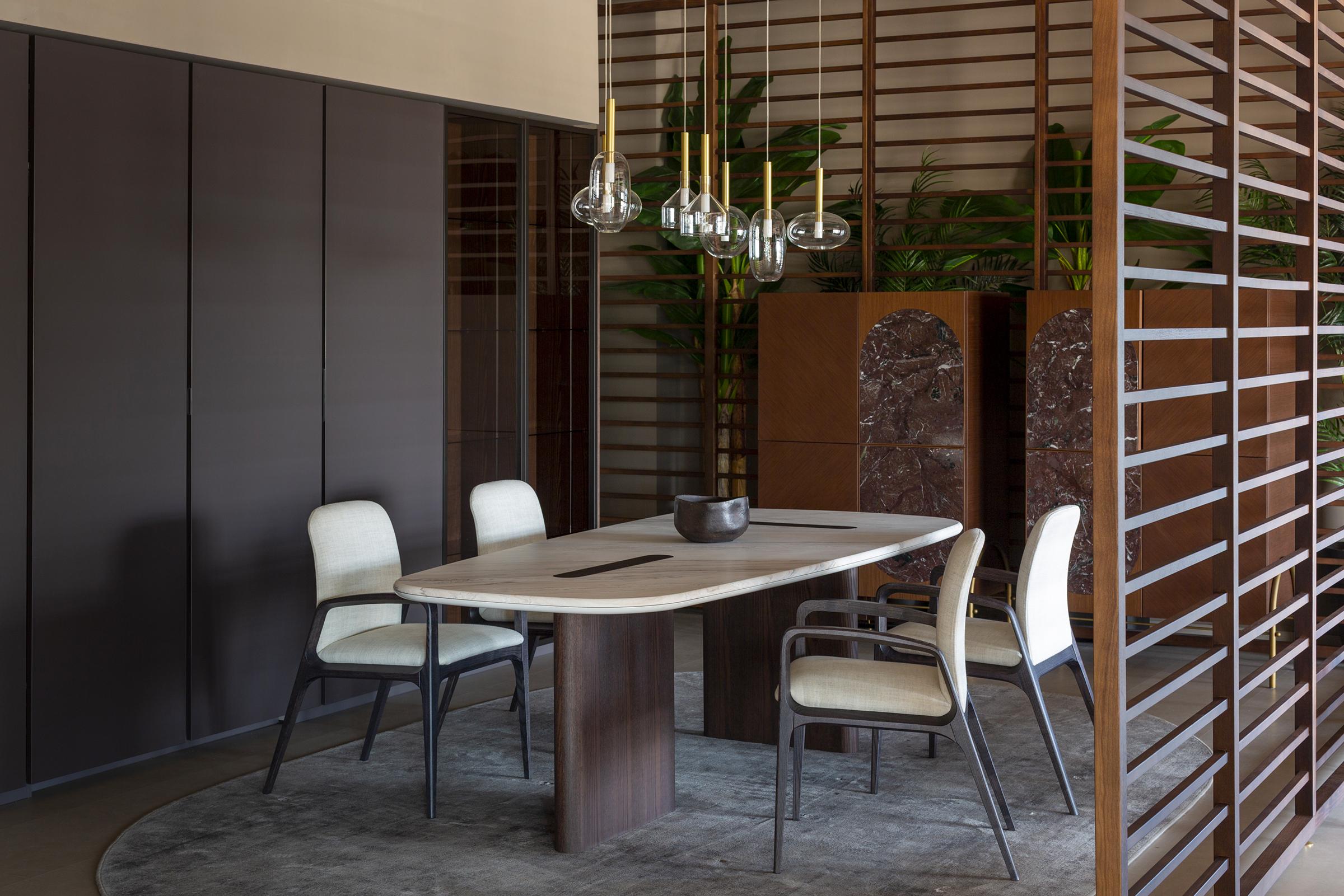 Les pieds en bois perpendiculaires émergent comme deux incrustations sur le plateau, définissant son esthétique essentielle. Il est mis en valeur par la combinaison de deux surfaces précieuses : le plateau laqué et les pieds en bois. Les