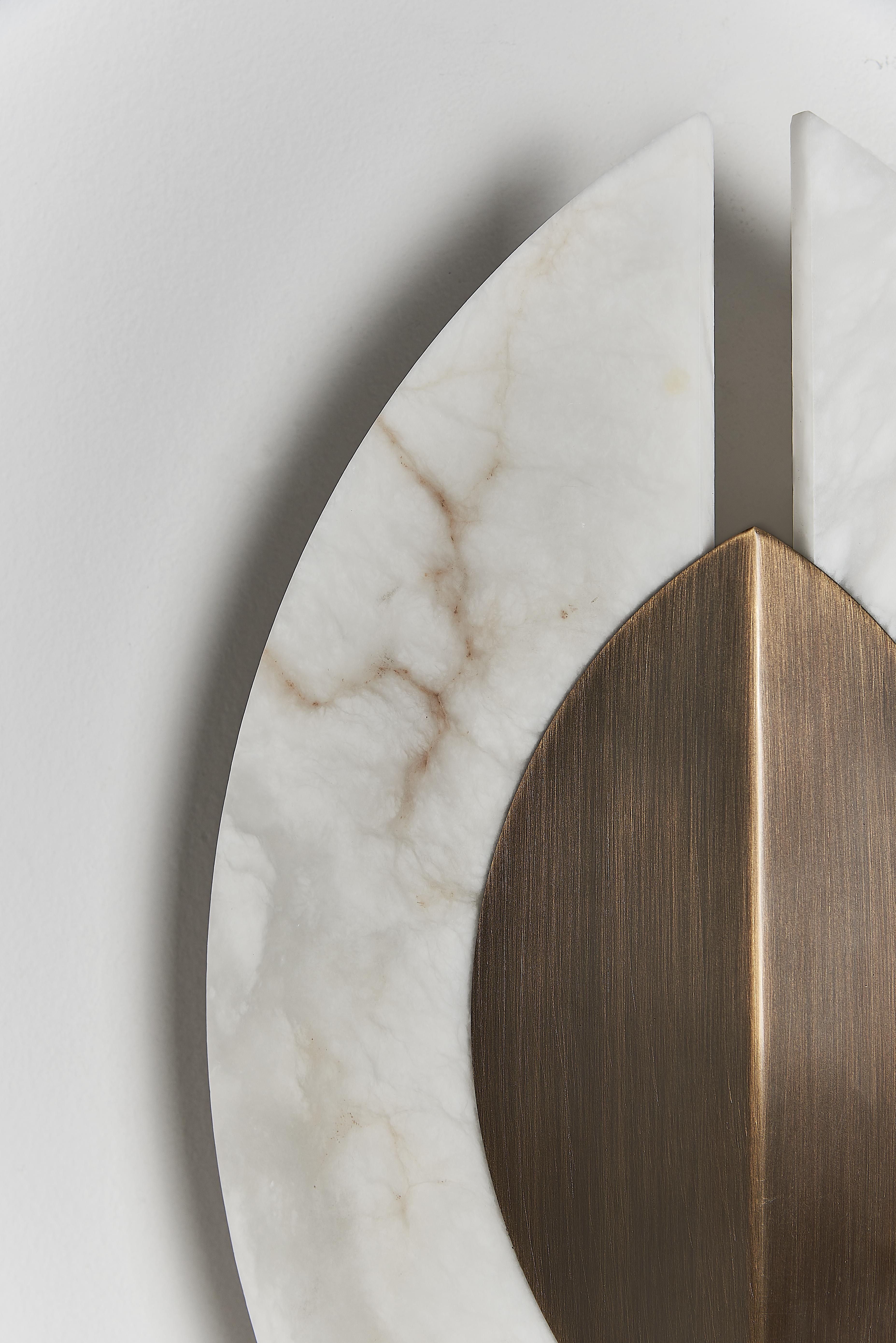 Shields wall sconce is a carefully crafted piece that combines elements of history, culture, and natural materials. The brushed bronze and alabaster materials create a tactile and visual experience that evokes the ancient shields of warriors, while