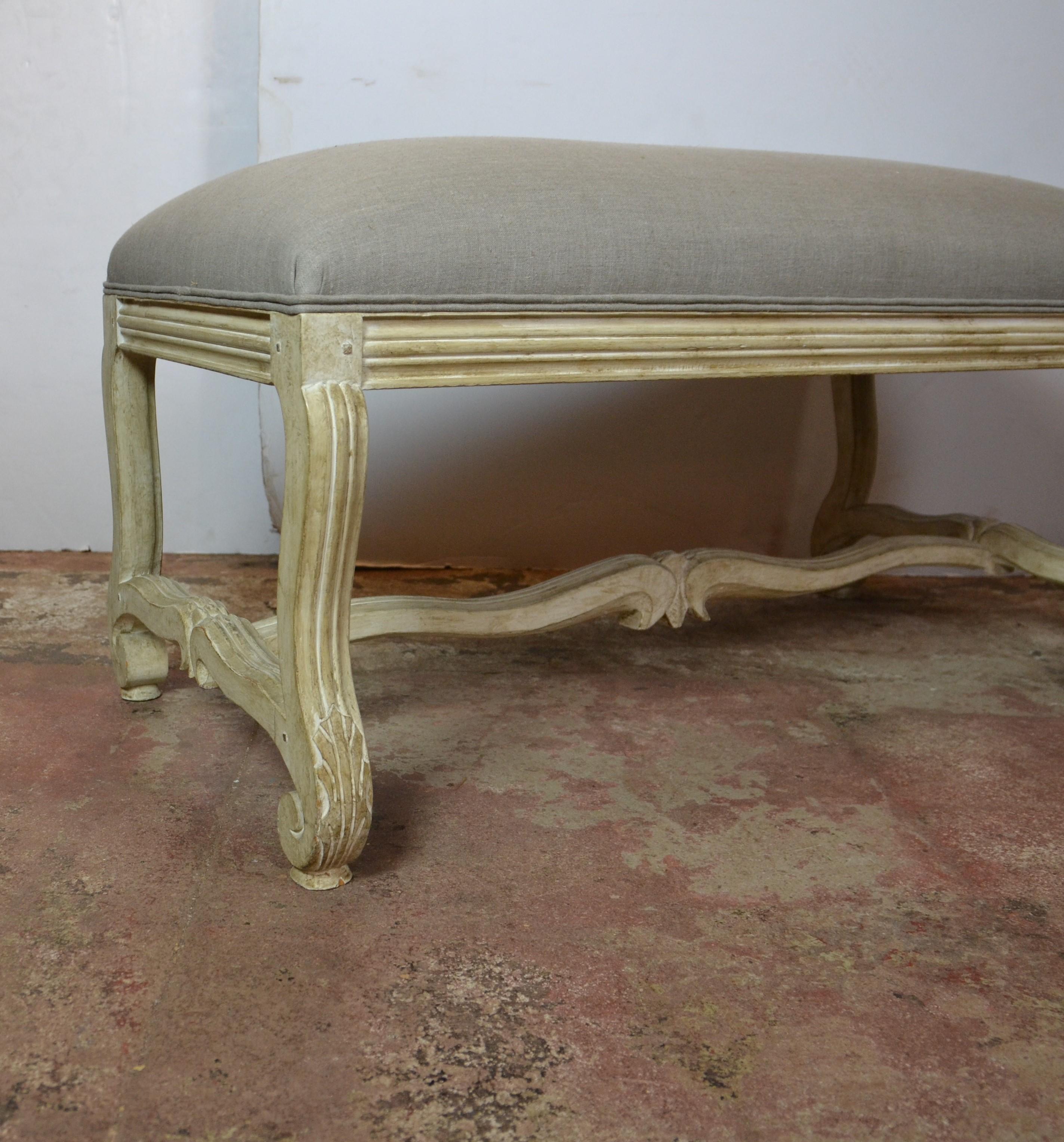 Natural finish wood-carved bench. Upholstered in light gray linen.