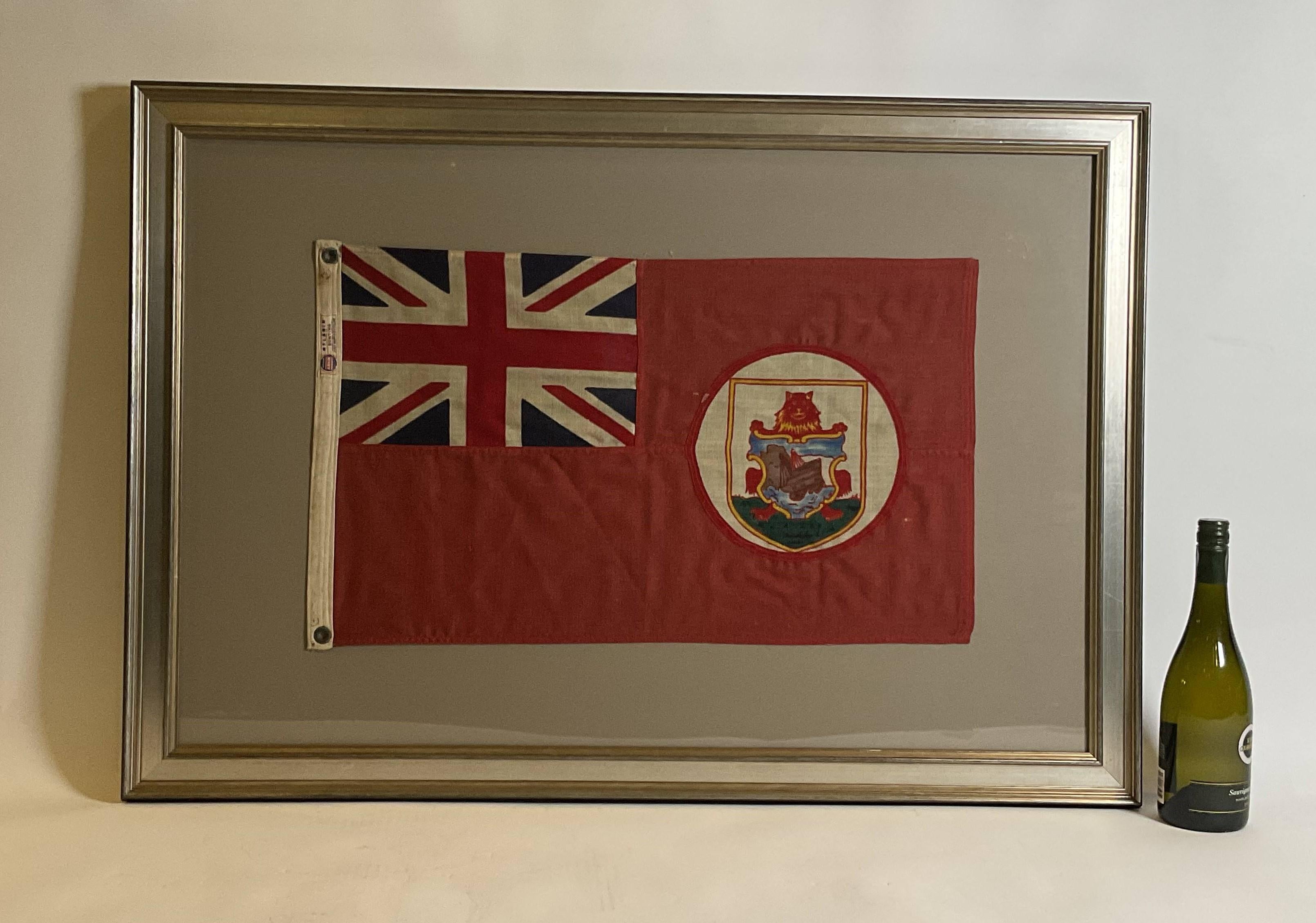 Antique flag for the Island of Bermuda. The flag of the British Overseas Territory of Bermuda as a red ensign was first adopted on 4 October 1910. British red ensign with the union flag in the upper left corner and the coat of arms of Bermuda.