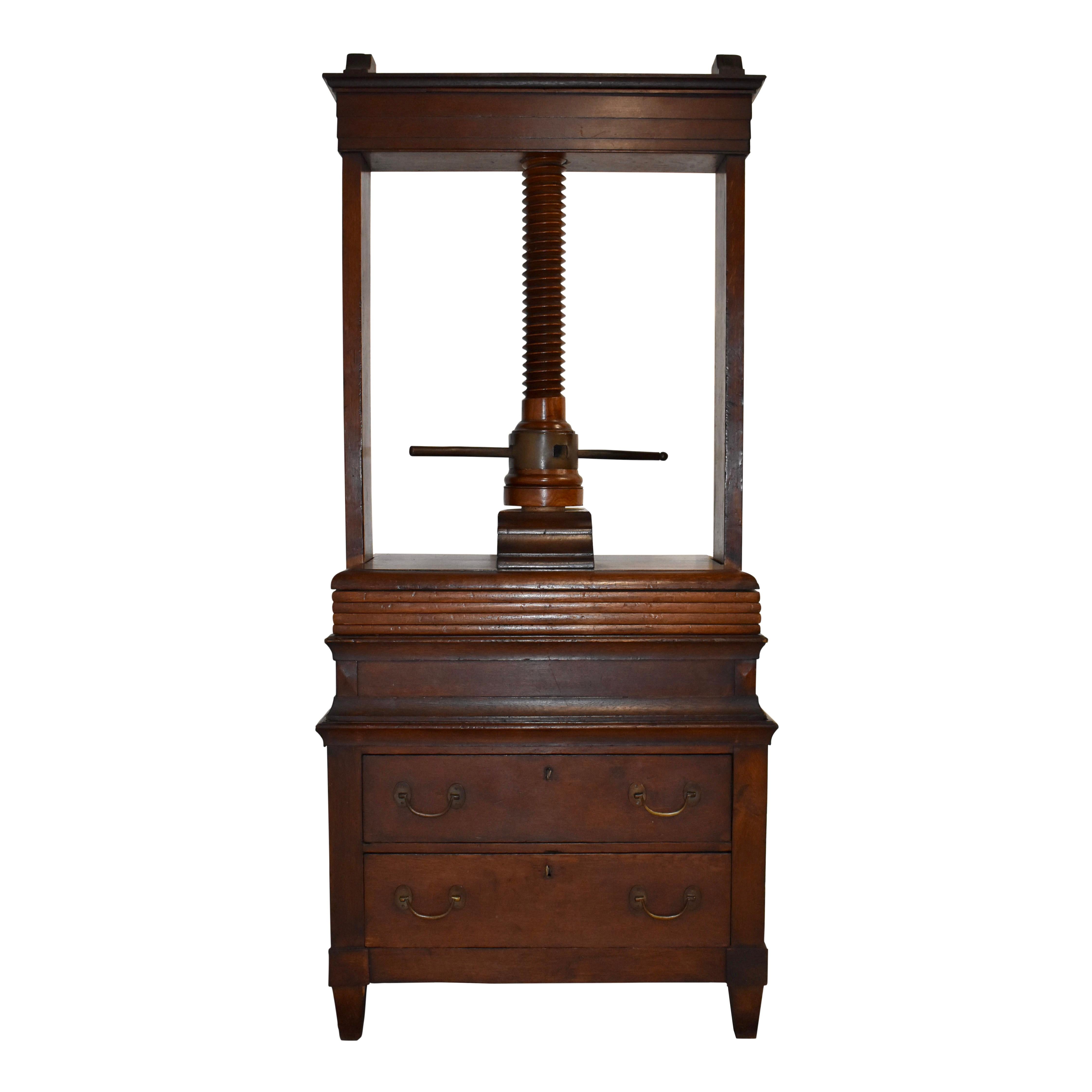 The press sits on a two drawer cabinet, convenient for storing freshly pressed items. Large presses like this one were valuable and occupied prominent rooms in the homes of wealthy owners. They were used to press garments, table napkins, aprons, and