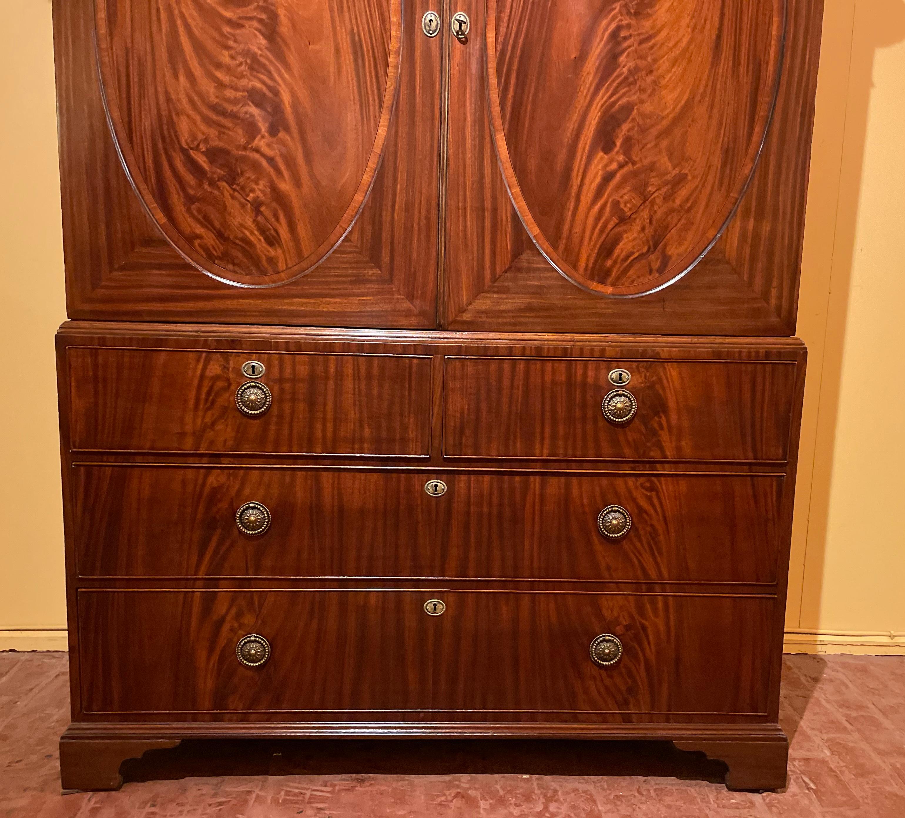Superb linen press in mahogany Sheraton period from the 18th century from England

The linen press is in two parts and is composed of 4 drawers at the bottom and two doors at the top
Very elegant cabinet witch has two ovals on the two doors. This