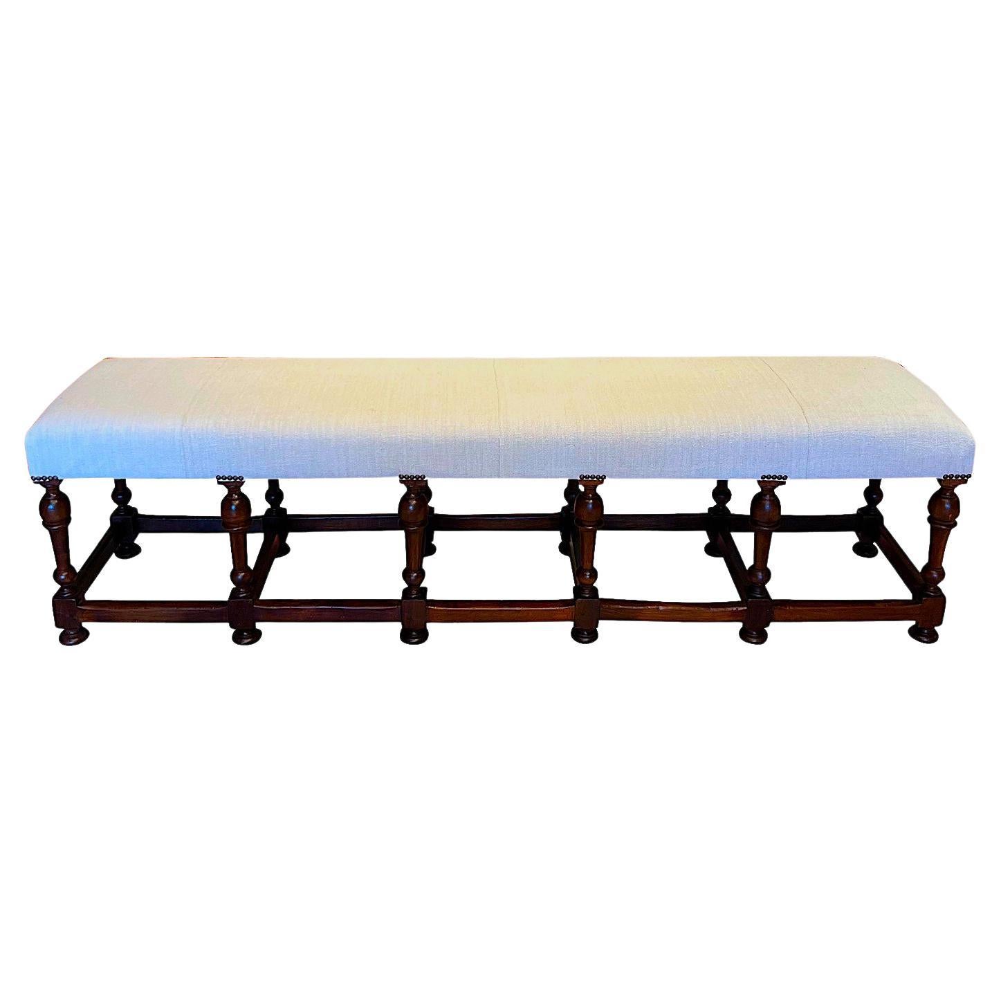 19th century Italian extra long bench with twelve turned legs. 
Legs are connected by straight wood stretchers.
Newly reupholstered in vintage hand spun Belgian linen.