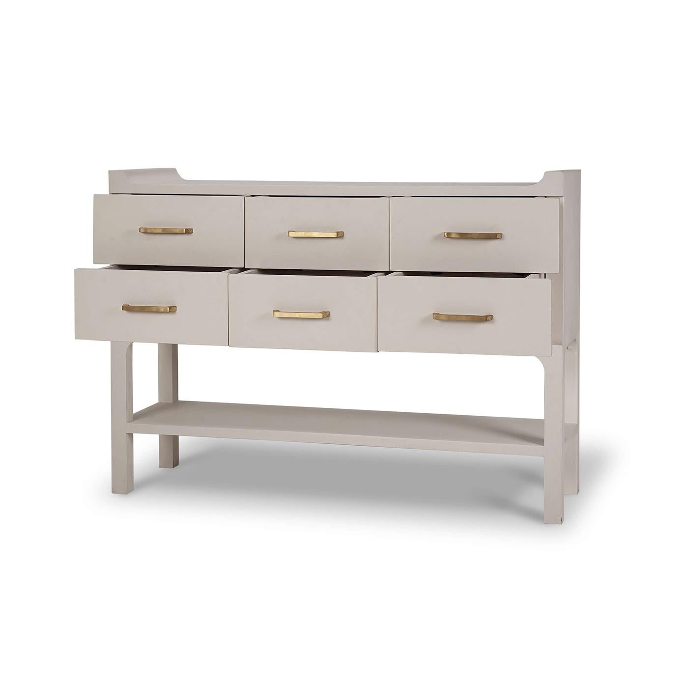 Crafted with a minimalist design, this table features clean lines and a chic, putty-colored linen wrap that perfectly captures the essence of Scandinavian style. The six spacious drawers, adorned with brass handles, provide ample storage for your