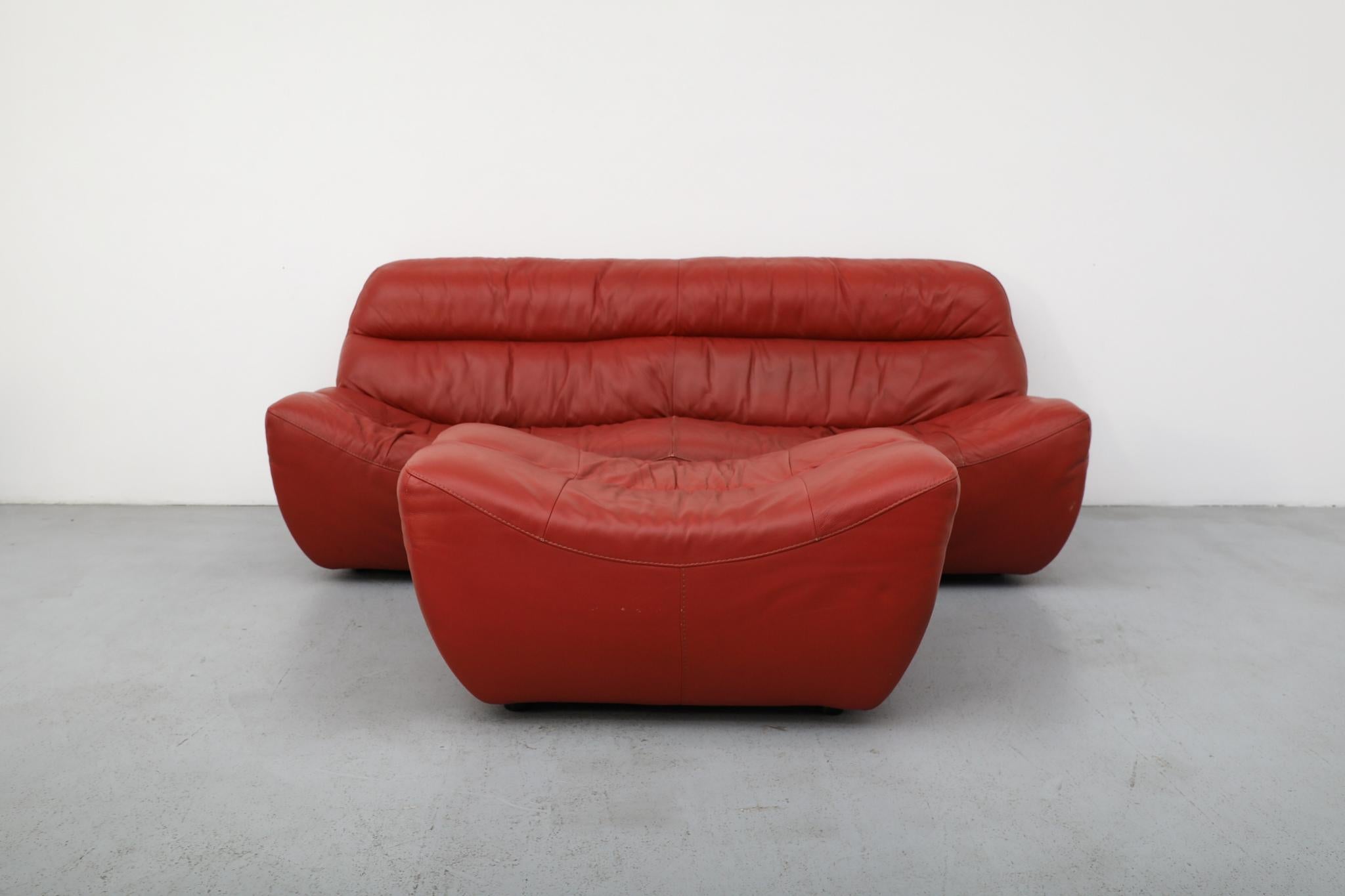 Ensemble canapé et ottoman en cuir rouge de style Ligne Roset du début des années 2000 par Calia Italia 2000's. Avec ses lignes spectaculaires, ses courbes intégrées et sa forme enveloppante, l'ensemble apporte à la fois un flair visuel et un