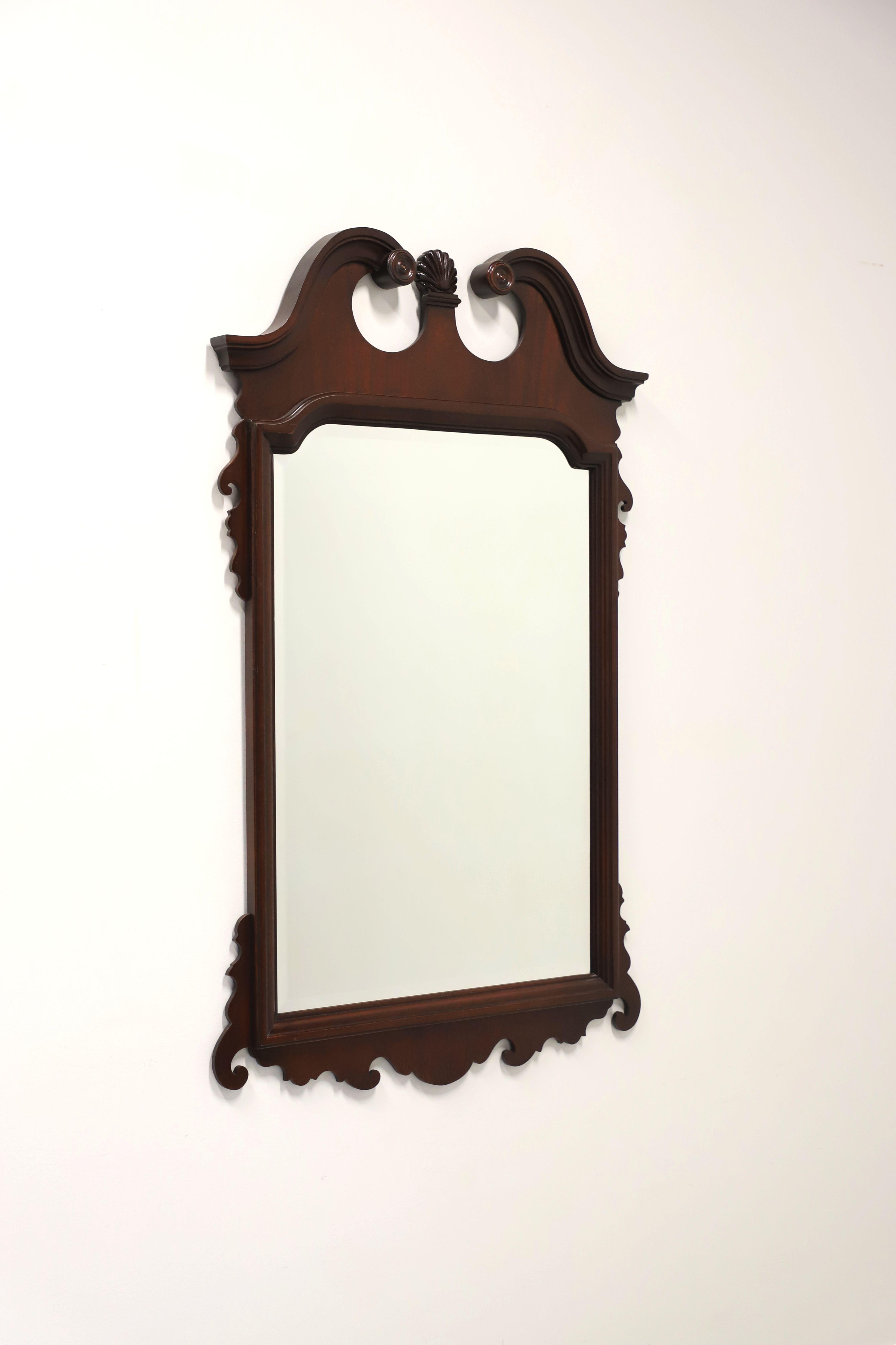 A Chippendale style wall mirror made by Link-Taylor, from their Heirloom Gallery. Beveled mirrored glass in a solid mahogany frame, decoratively carved, and a broken arch top with center medallion. Made in Lexington, North Carolina, USA, circa
