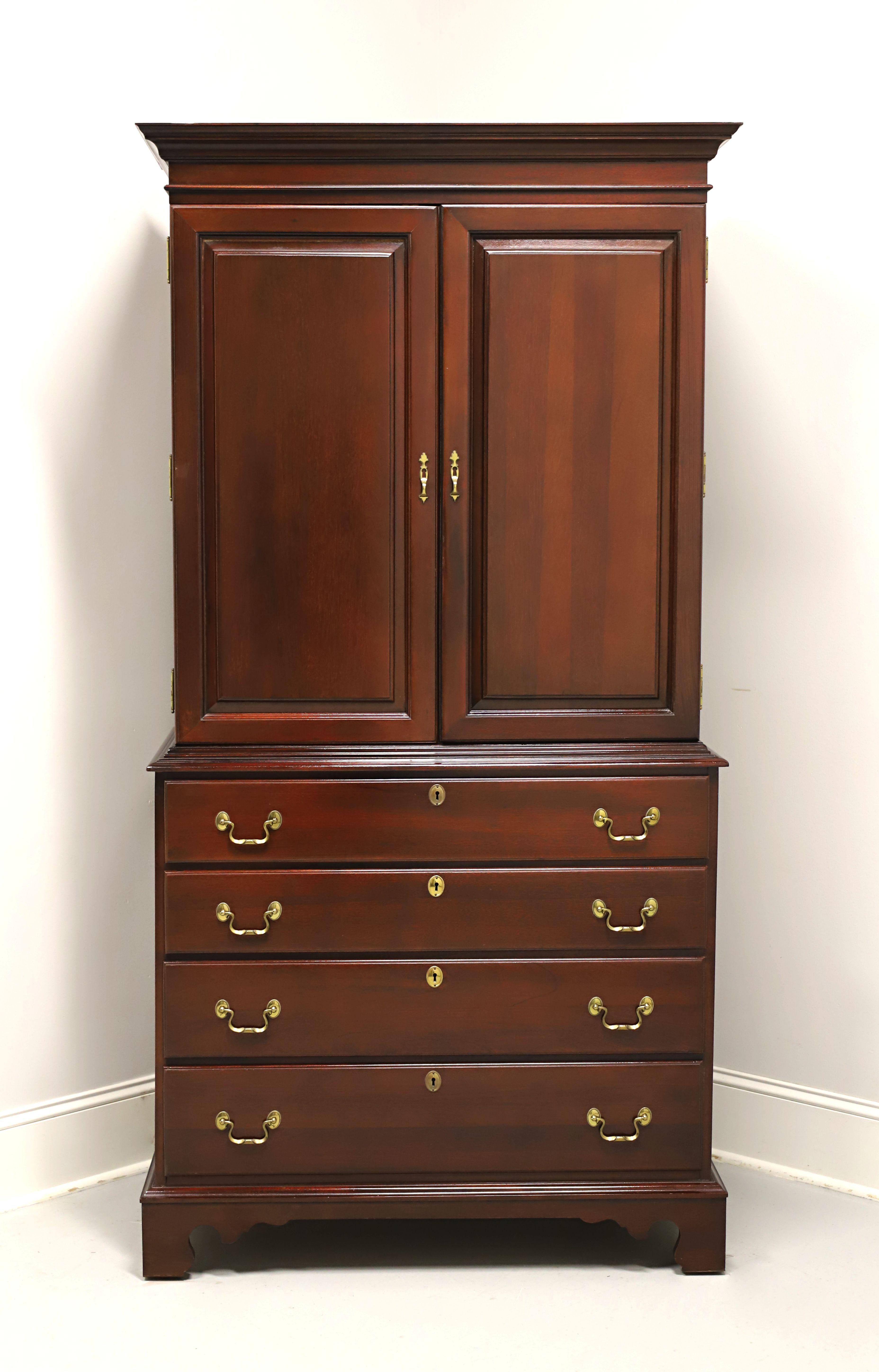 A Chippendale style armoire / linen press by Link-Taylor, from their Heirloom Gallery. Solid mahogany with brass hardware, crown moulding to top, ogee edges, and bracket feet. Upper area features two solid fold flat doors revealing an interior with