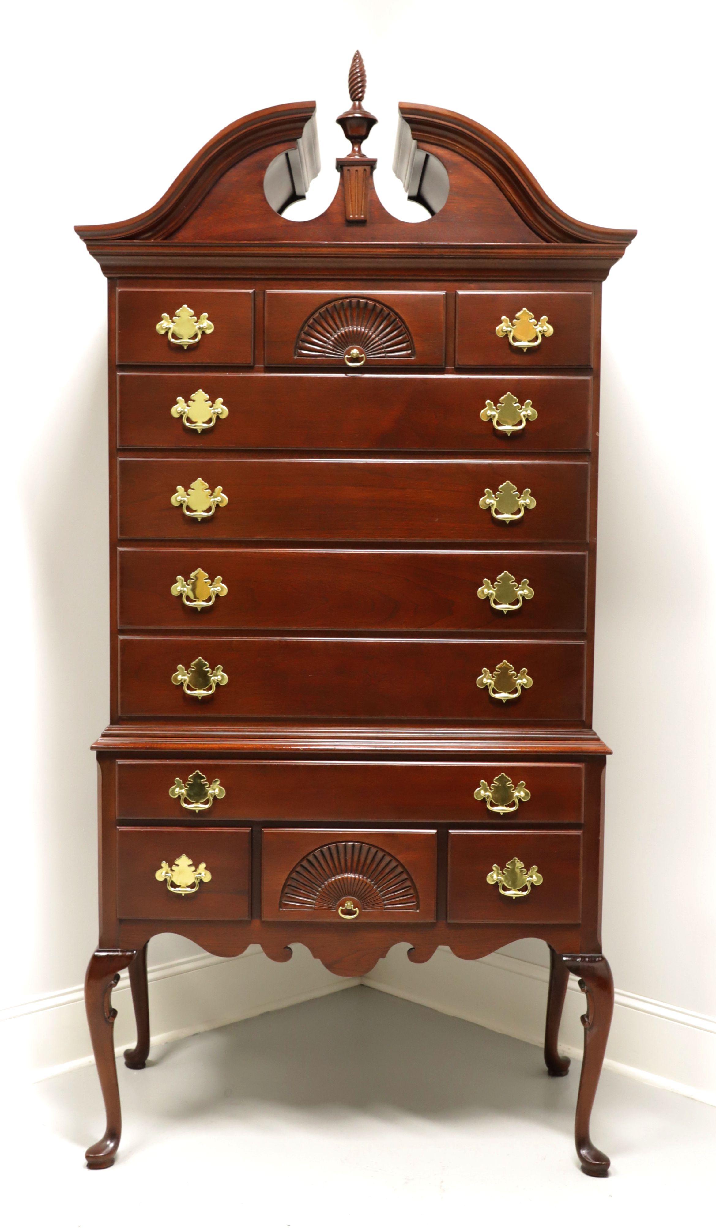 A highboy chest in the Queen Anne style made by Link-Taylor. Solid heirloom mahogany with brass hardware, a full pediment top, center finial, cabriole legs and pad feet. Features eleven dovetail drawers of various sizes, two with carved fan fronts.