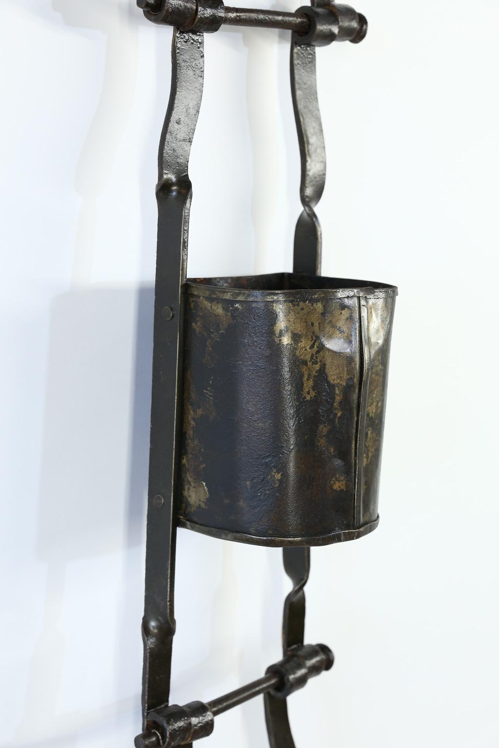 This is a lovely set of three linked French coal buckets. The natural aging of the piece brings out a rich combination of black and grey. We have added a custom iron bracket so it can easily be hung on a wall. It can be used as a display piece for