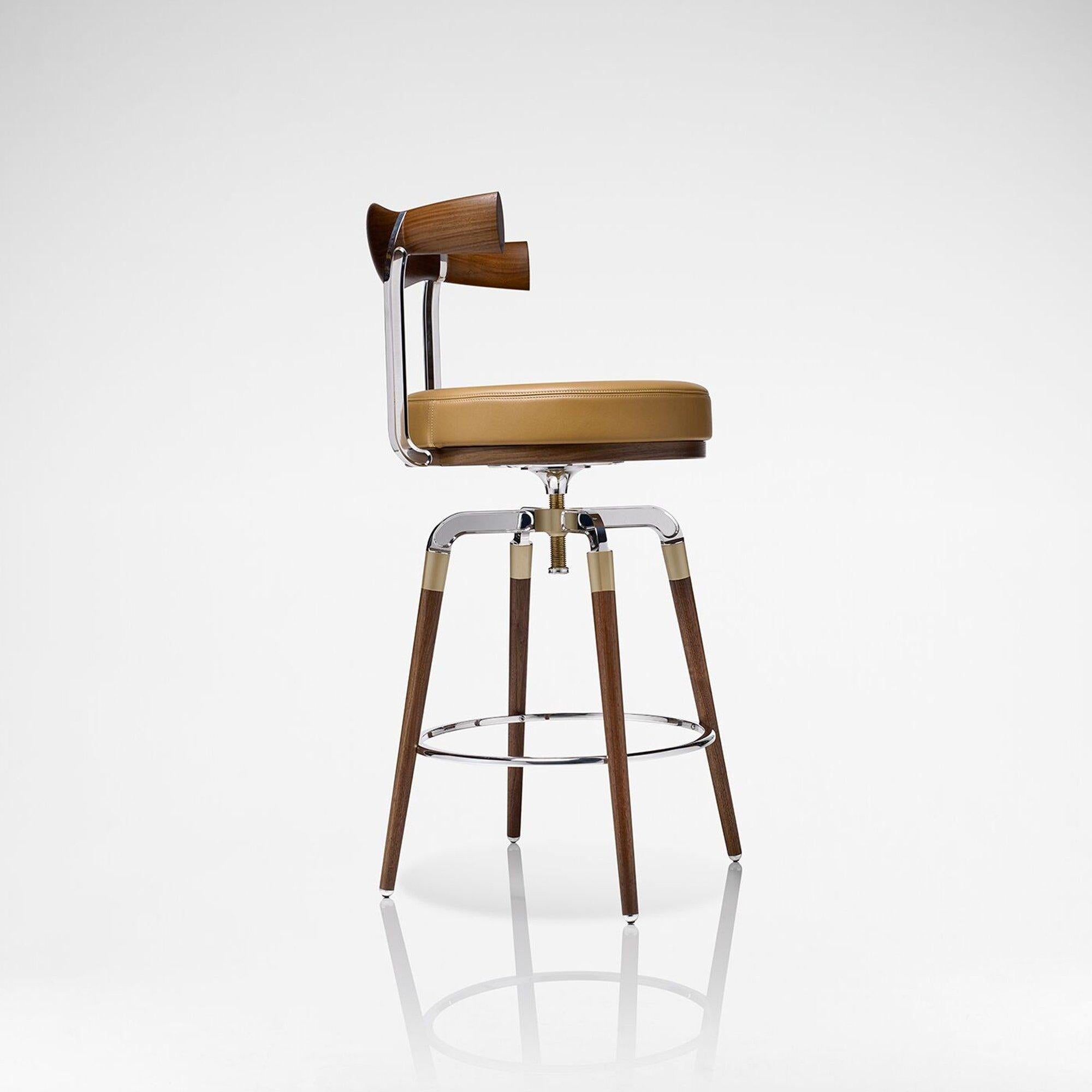 Crafted in walnut, engineered brushed brass and polished aluminum, the rifle bar stool has an adjustable seat height making this ideal for your home bar.

The curved seat rest of the chair and distinctive barrel-shaped legs are a continued