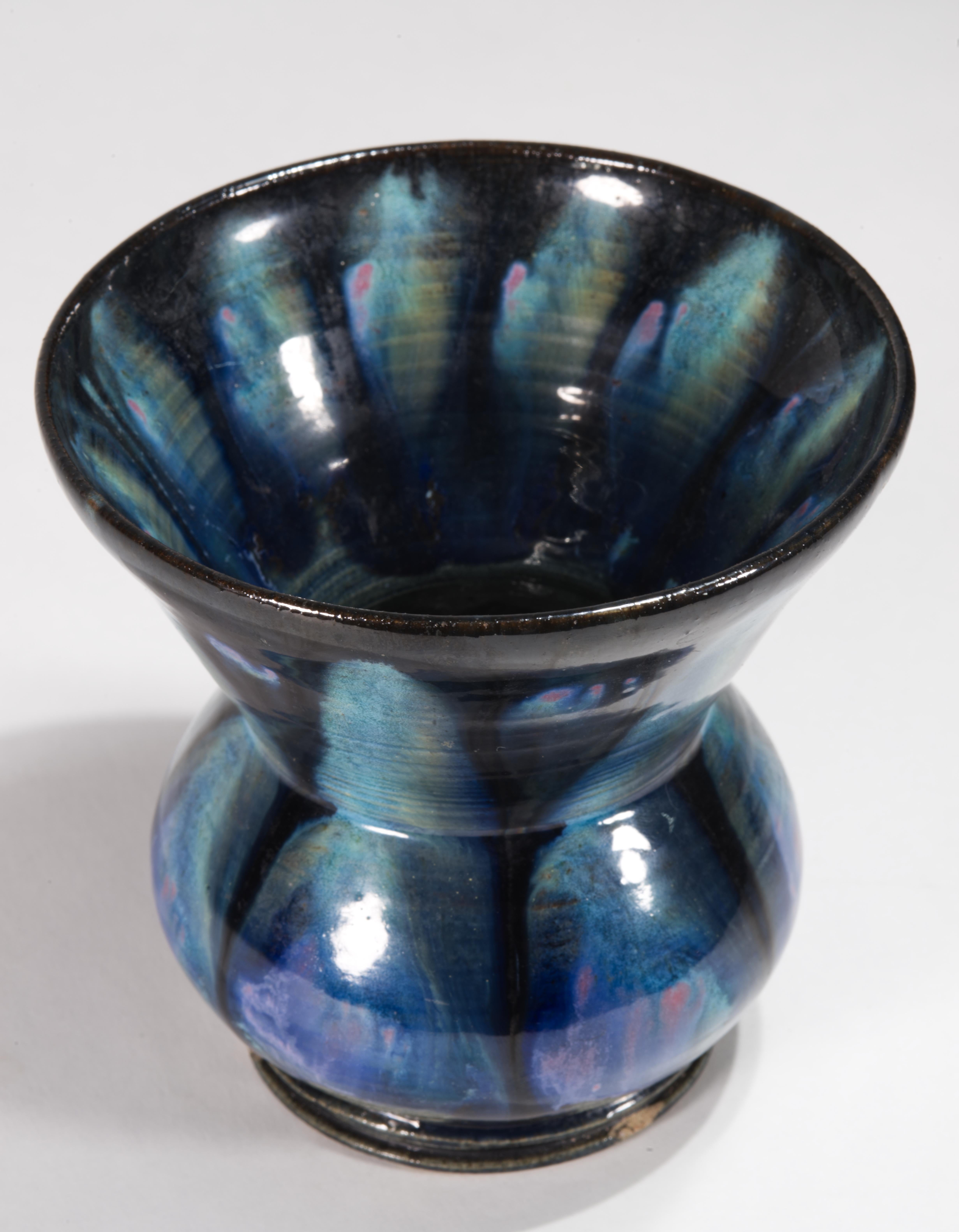  Il vaso scultoreo d'epoca presenta un corpo bulboso con un bordo largo e pronunciato; è decorato con un complesso smalto a goccia nei toni del blu, del verde acqua e del verde con accenti rosa beige. Le parti del vaso vicino al fondo sono