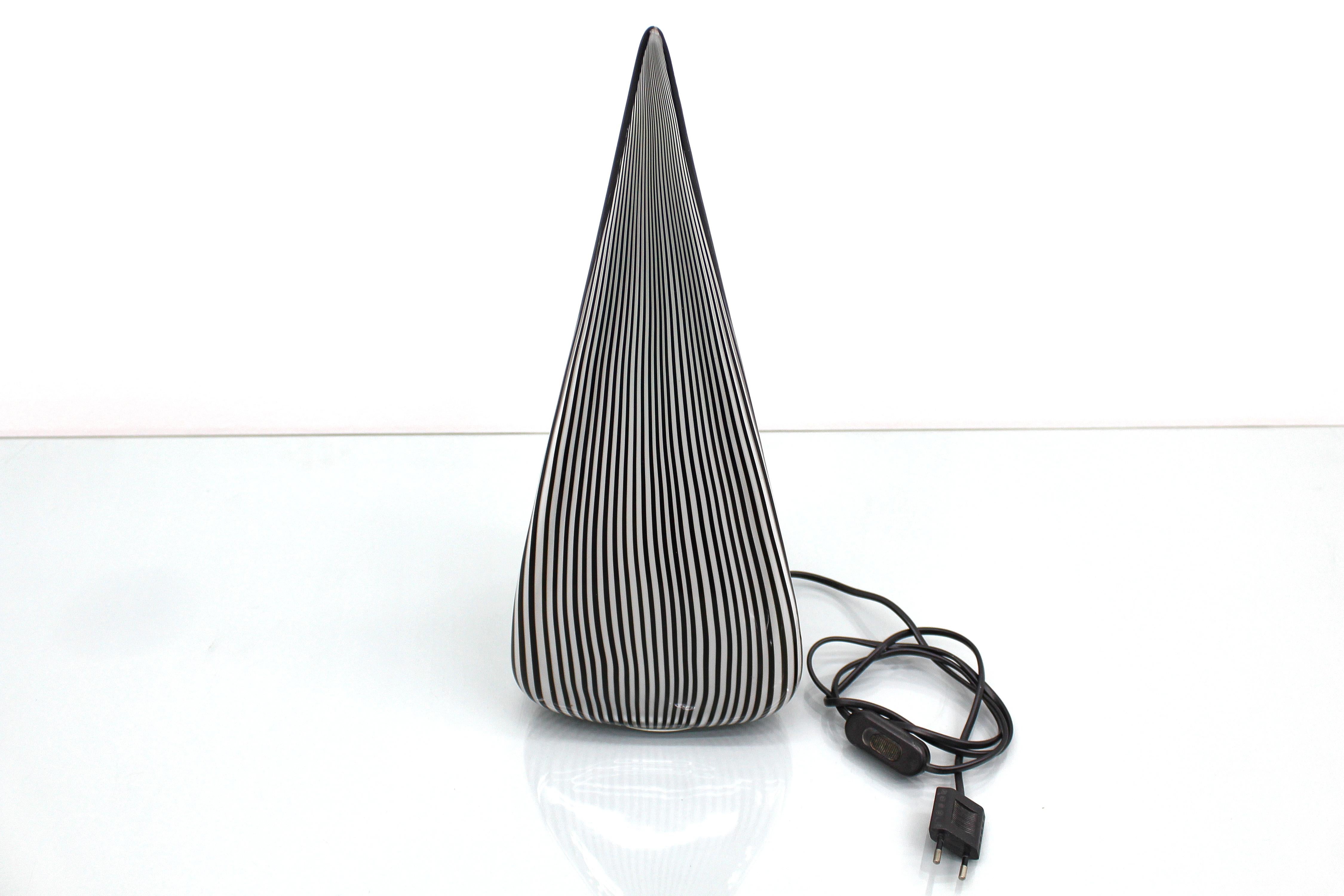 Elegant pyramidal table lamp in Murano blown glass with black and white canes that give a suggestive lighting effect. Attributable to the Muranese master Lino Tagliapietra, for Effetre International, Italy, 1980s. At the bottom is a portion of the