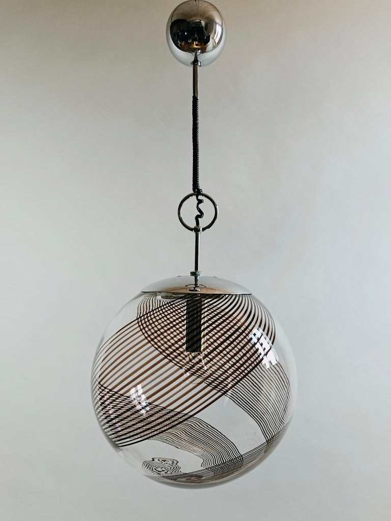 Lino Tagliapietra for La Murrina rare one-light large pendant lamp in Murano art glass and chrome.
The transparent glass shade features the classic double spiral strip movement that wraps around it from the bottom to the top, providing a fascinating