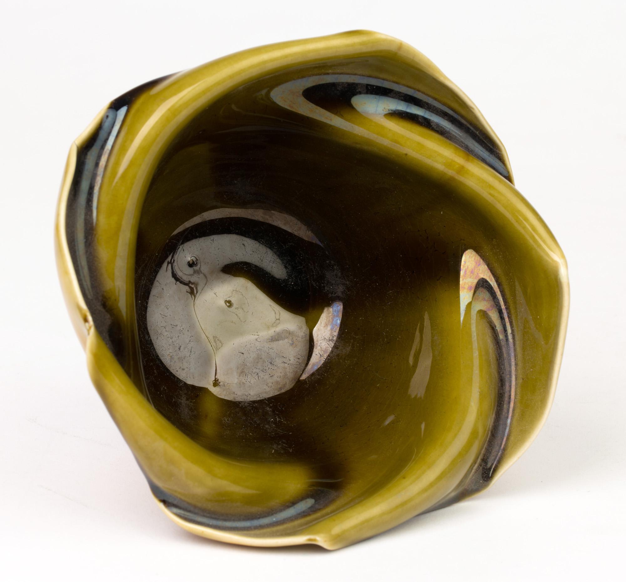 A stylish Aesthetic Movement art pottery vase designed by Christopher Dresser for Linthorpe and dating circa 1885. The rounded pottery vase is of collapsed form with a folded hankerchief styled rim and decorated in thick flow green glazes to the