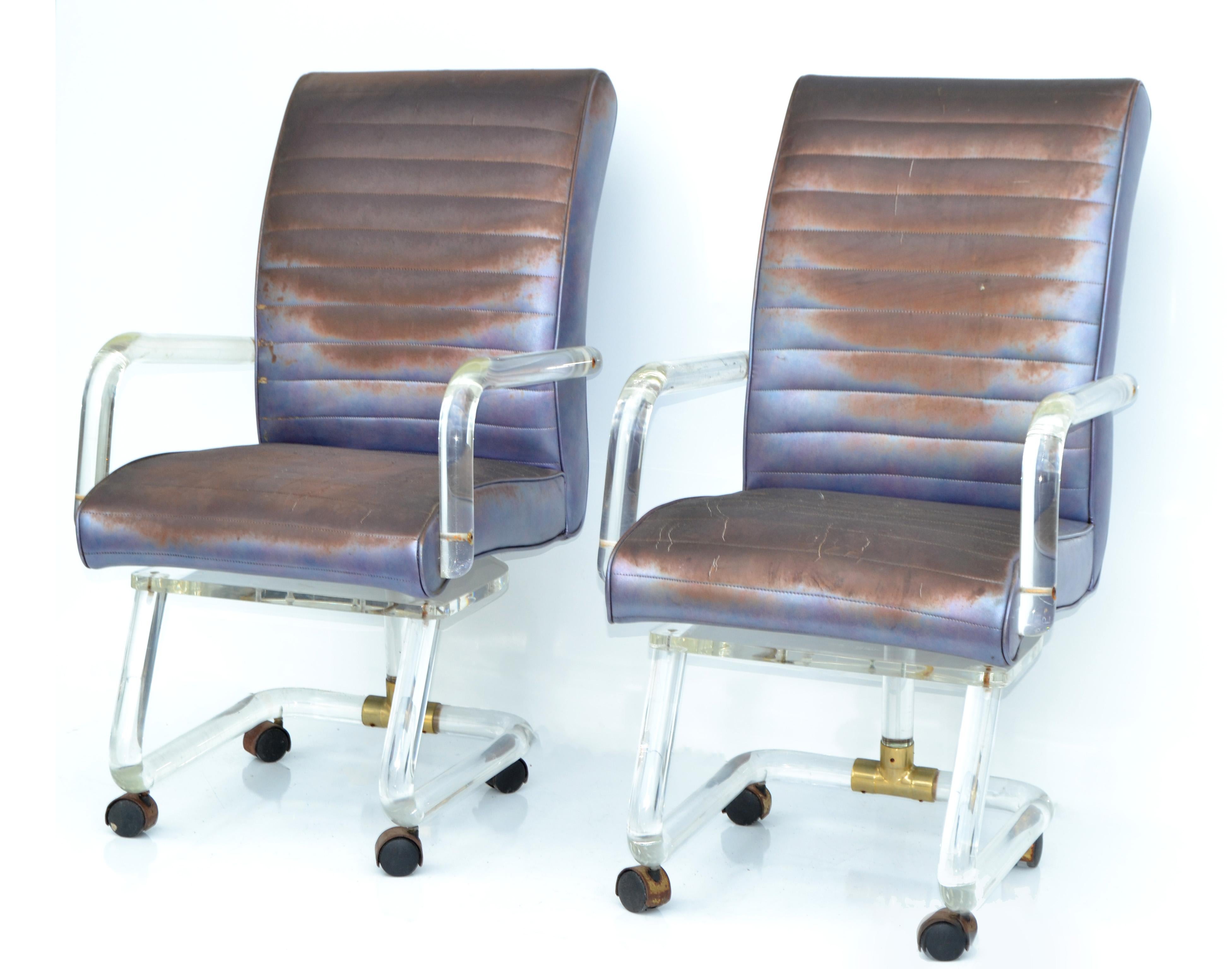 Mid-Century Modern pair of lion in frost lucite dining, office chairs or armchairs on casters with brass detailing made in America in the late 20th century.
The original distressed looking Upholstery in electric blue needs to be redone.
The Lucite