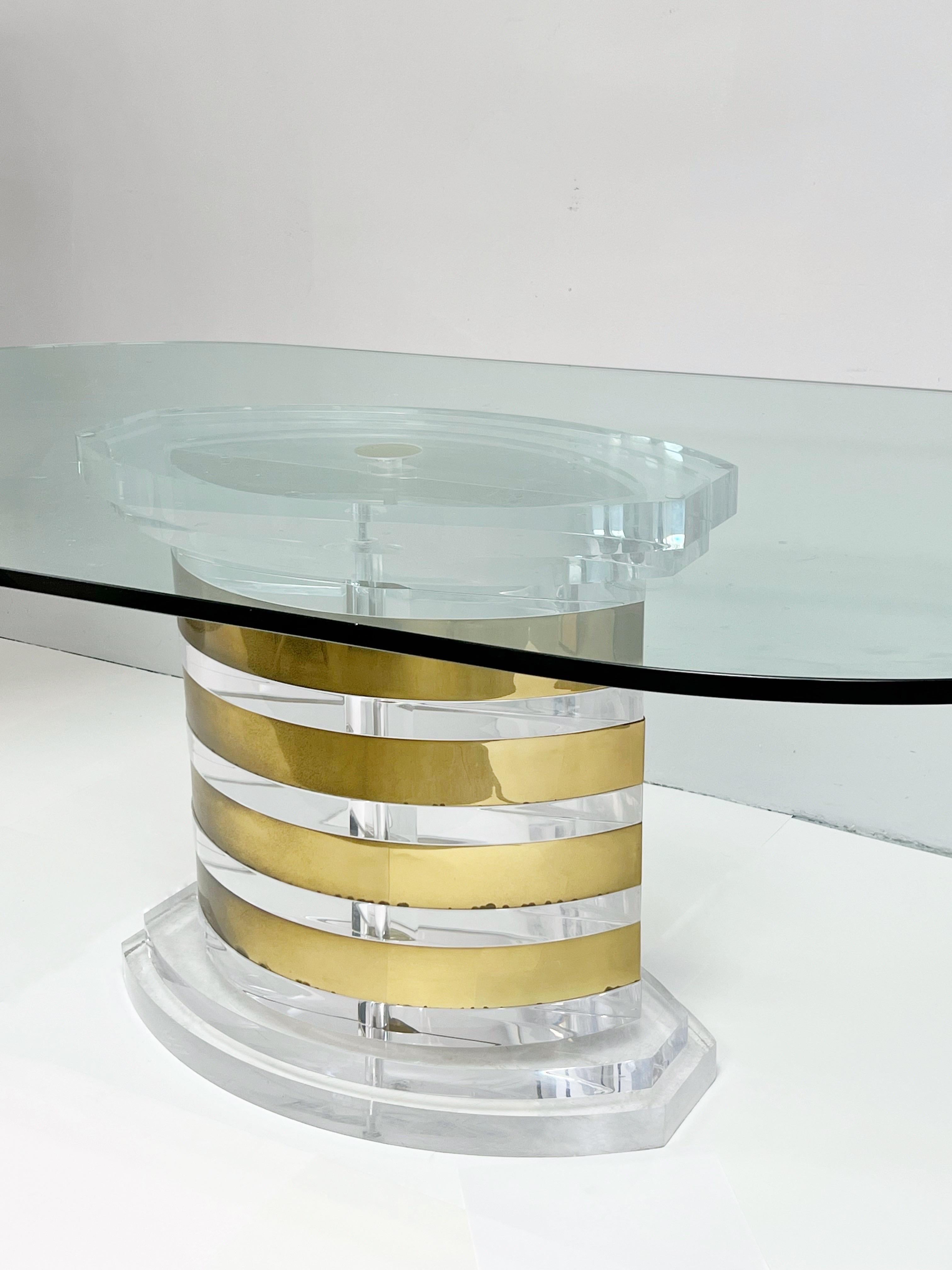 Spectacular table by Lion in Frost. The large pedestal is solid lucite with brass bands. Racetrack 3/4” glass top.