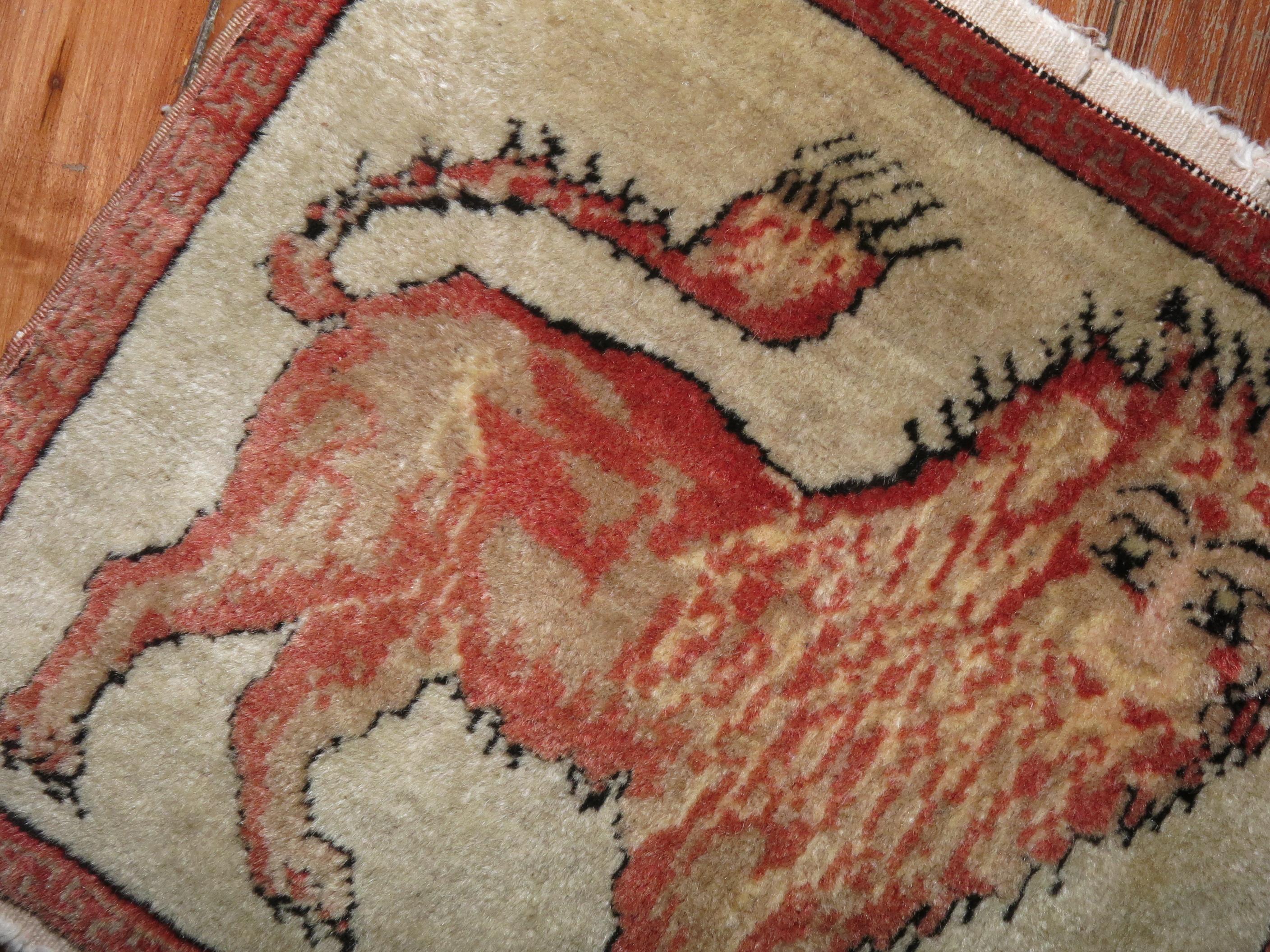 Eine winzige Teppichmatte aus dem frühen 20. Jahrhundert aus Zentralasien, höchstwahrscheinlich aus der Region Khotan in Ostturkestan. Ein Löwe steht allein auf elfenbeinfarbenem Grund. Er ist ziemlich klein, so dass man ihn leicht überall