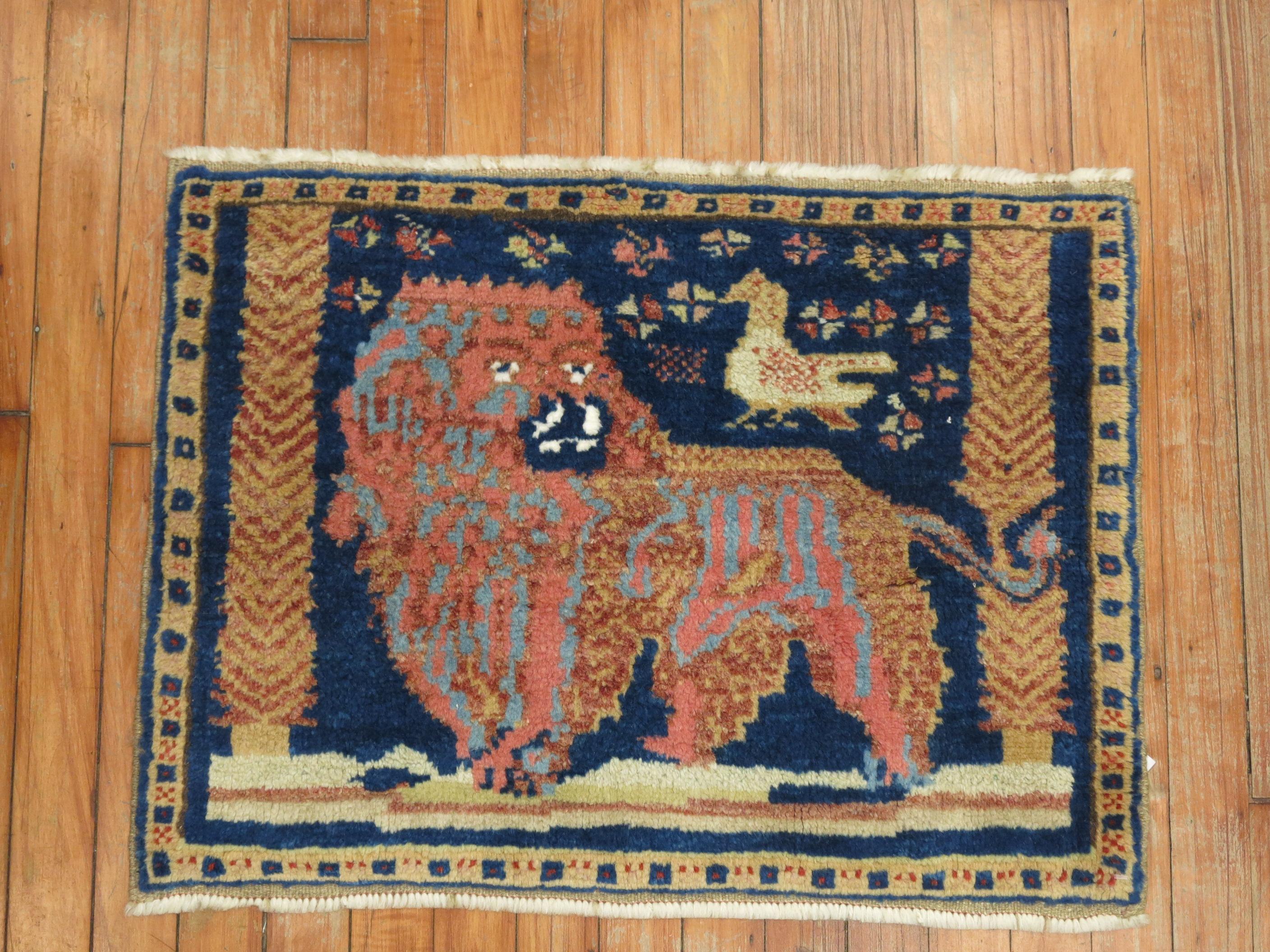 A mid-20th century Turkish rug depicting a stand alone lion with a small pigeon hovering over on a deep blue colored field.