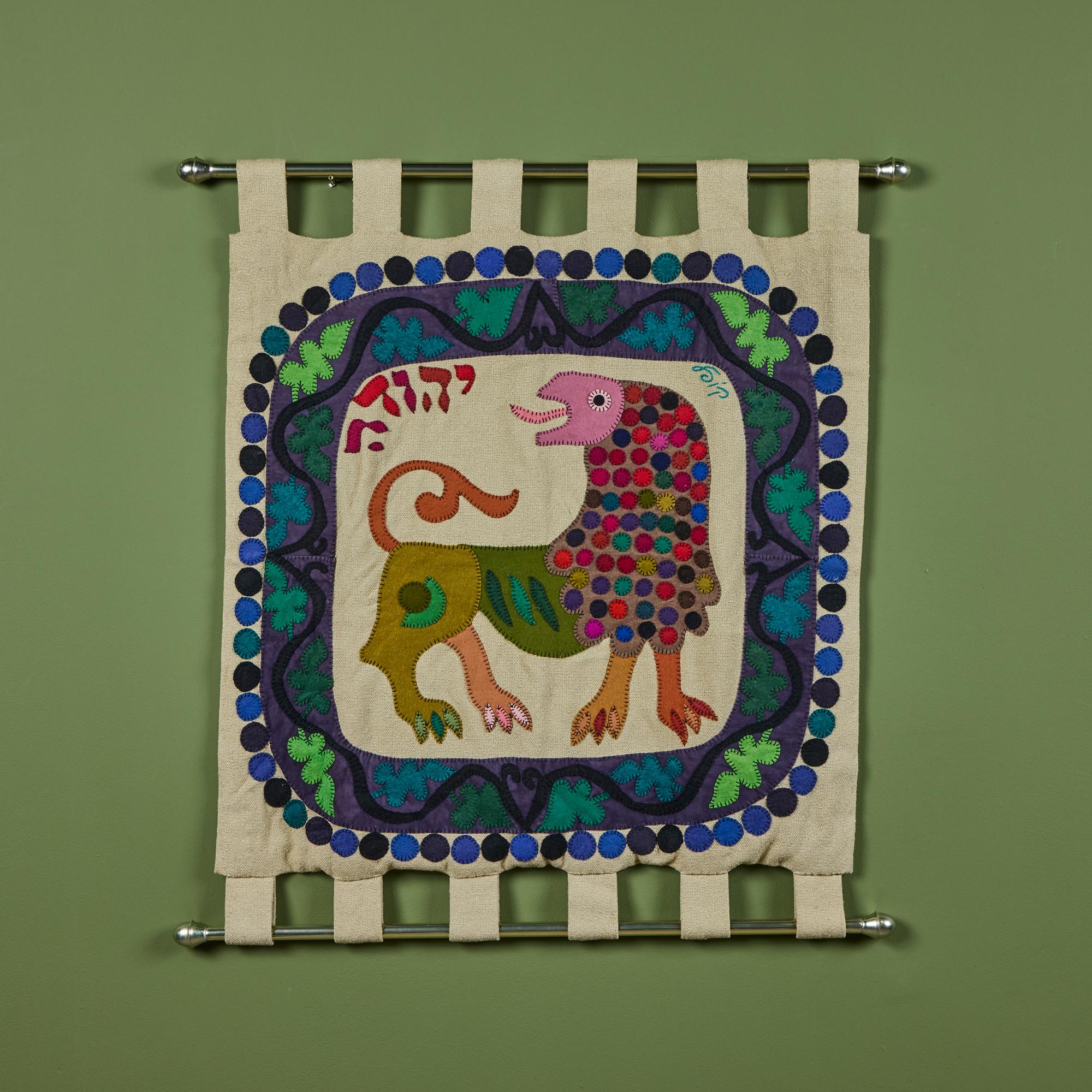 Wandteppich, ca. 1960er Jahre, von dem israelischen Künstler Kopel Gurwin. Die handgestickte Wollfilzapplikation zeigt einen Löwen in der Mitte, bekannt als der Löwe von Juda, mit einer dekorativen Umrandung in Blau- und Grüntönen. Signiert vom